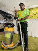 A man in a green shirt is holding a vacuum