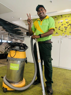 A man in a green shirt is holding a vacuum