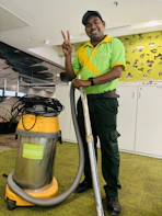 A man in a green shirt is holding a vacuum
