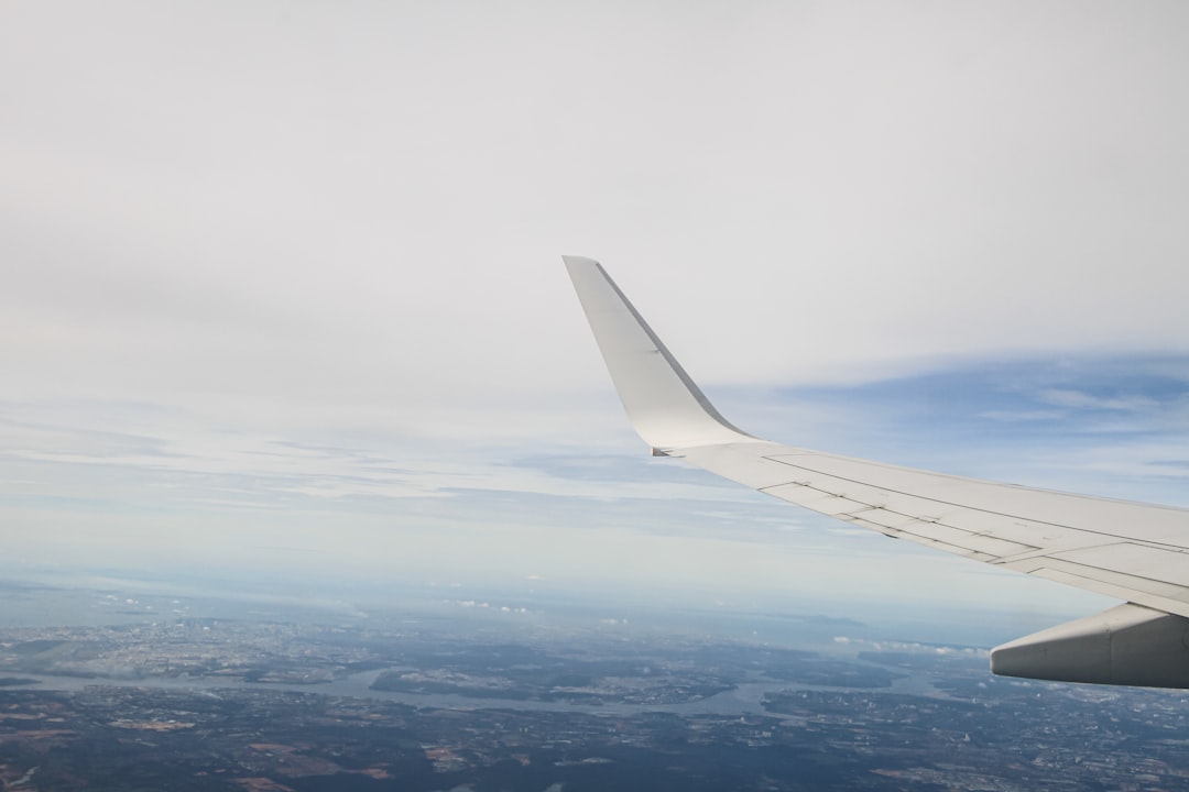 The wing of an airplane flying over a city,