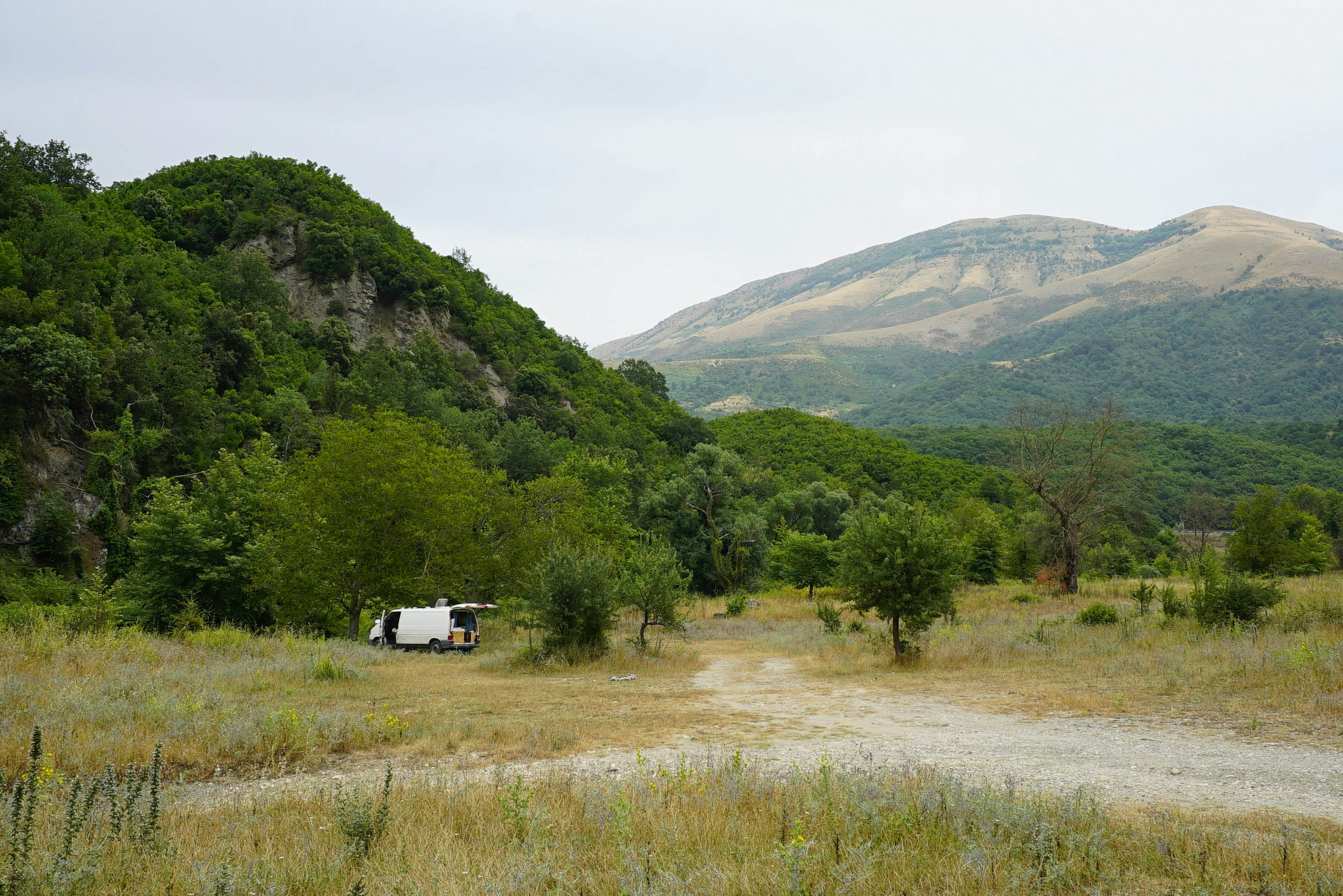 A dirt road in a field with mountains in the background