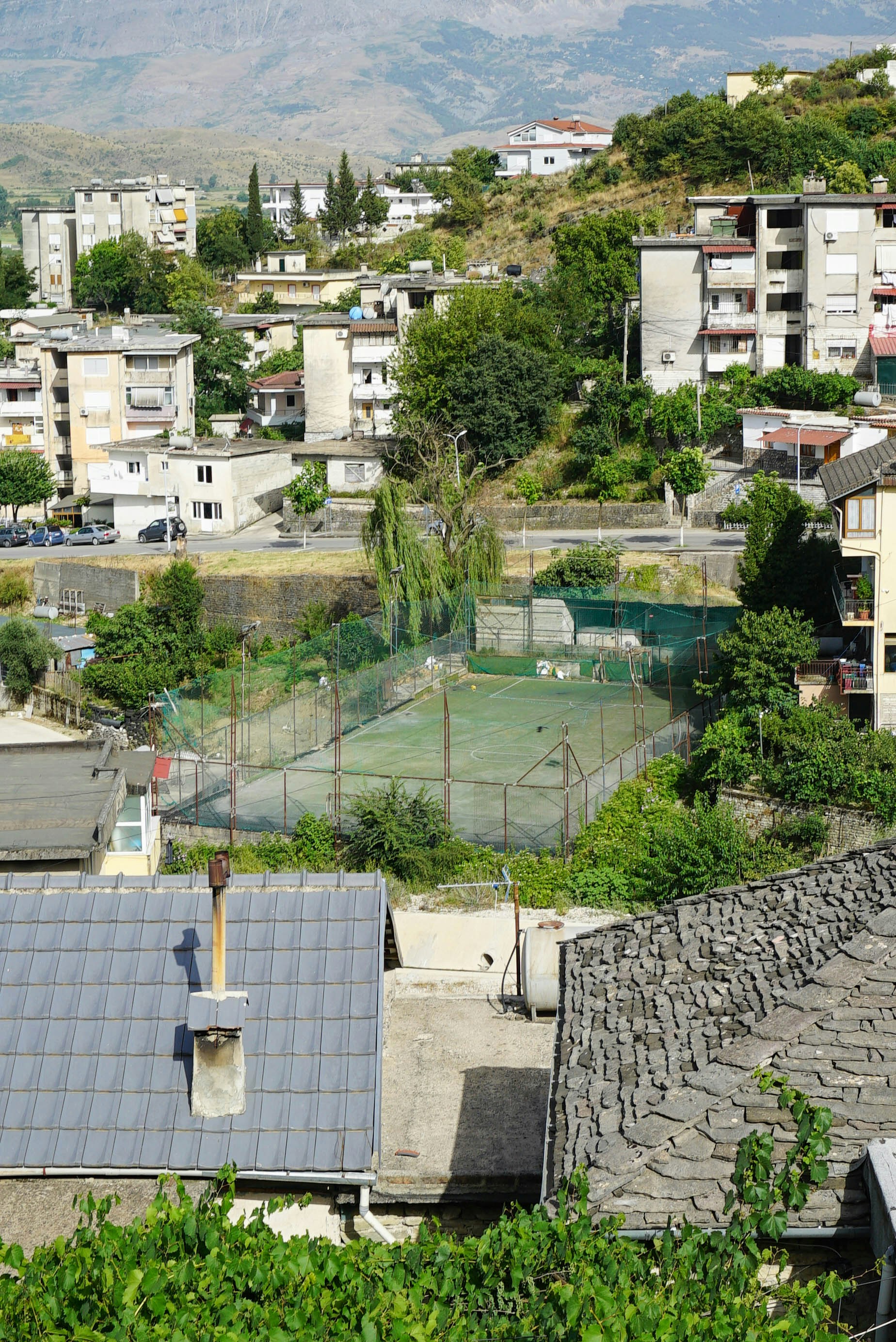 A view of a city with a tennis court in the foreground