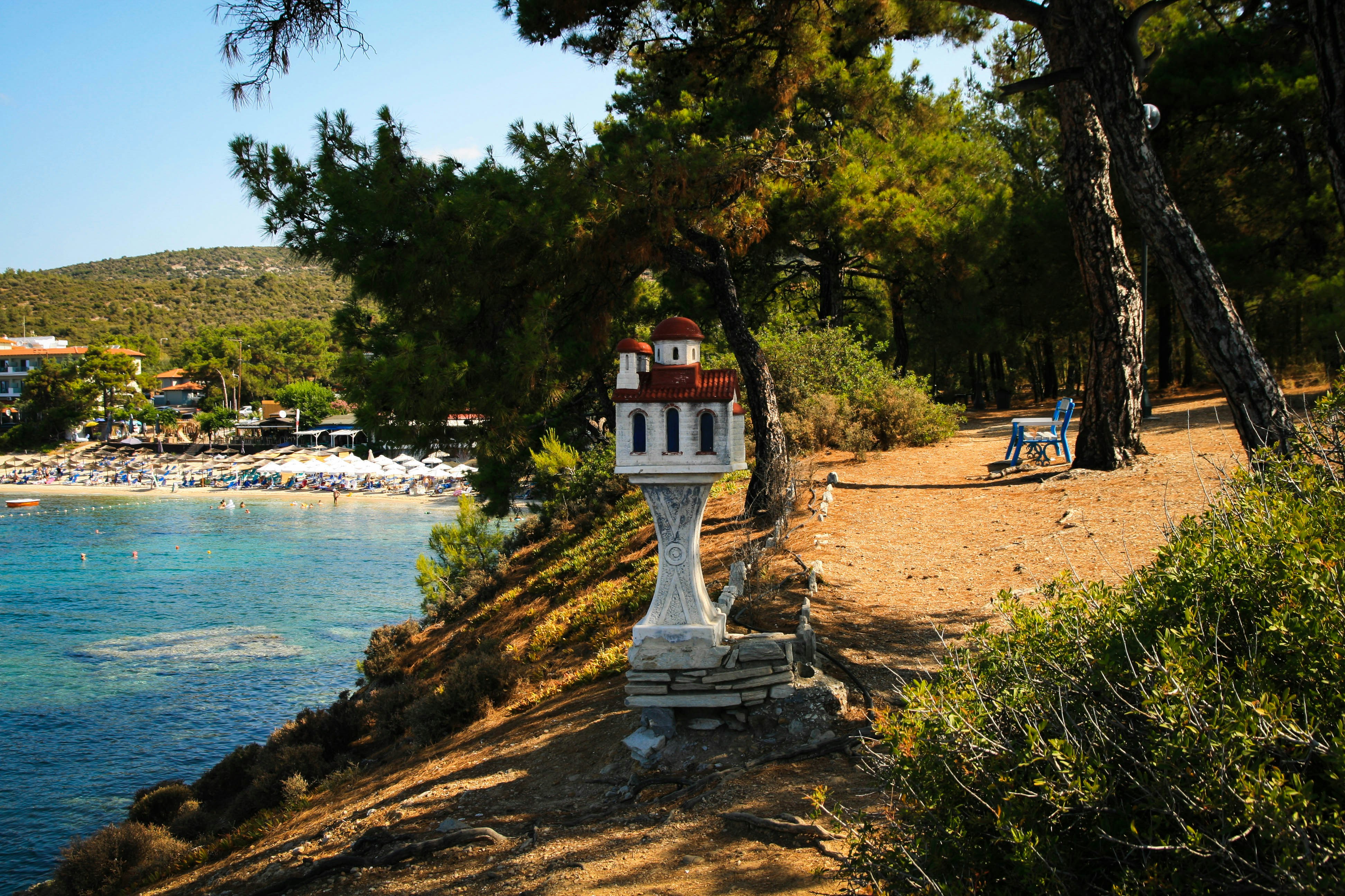 Eine weiße Uhr steht am Straßenrand neben einem Gewässer