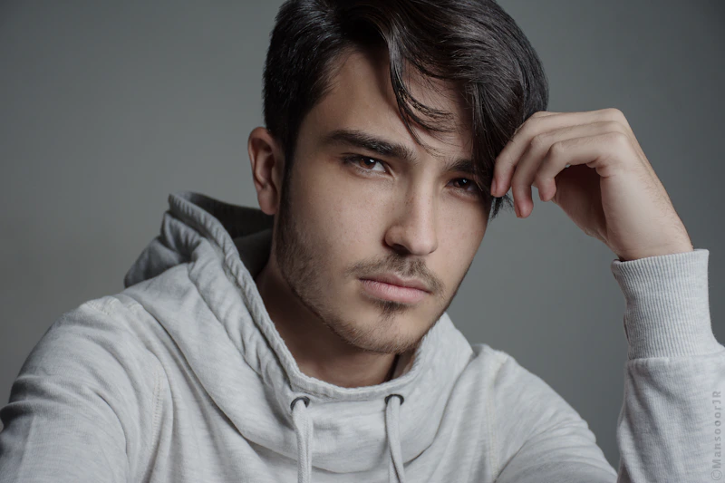 hombre joven con hoodie gris posando
