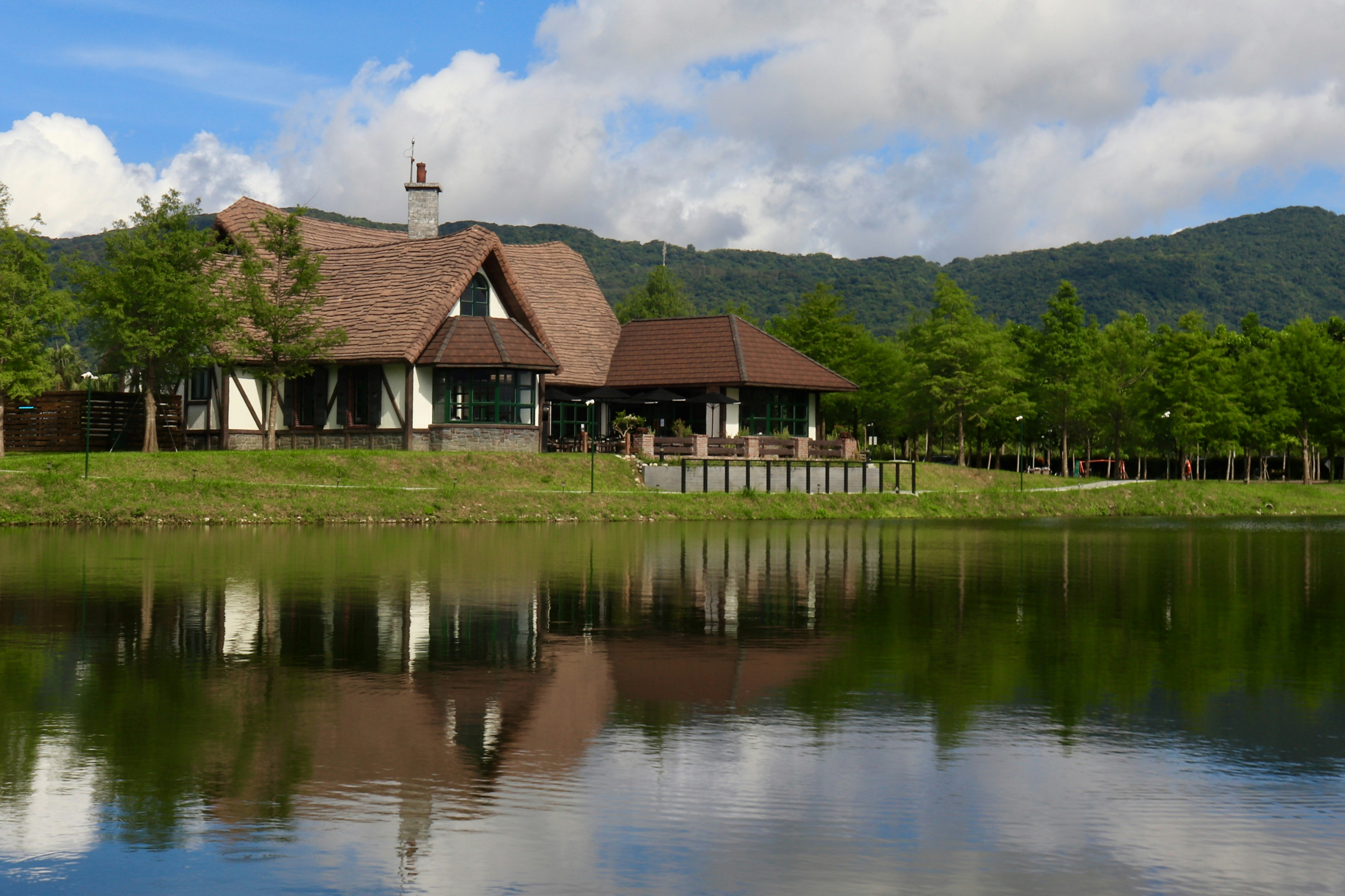 A large house sitting on top of a lush green field next to a lake