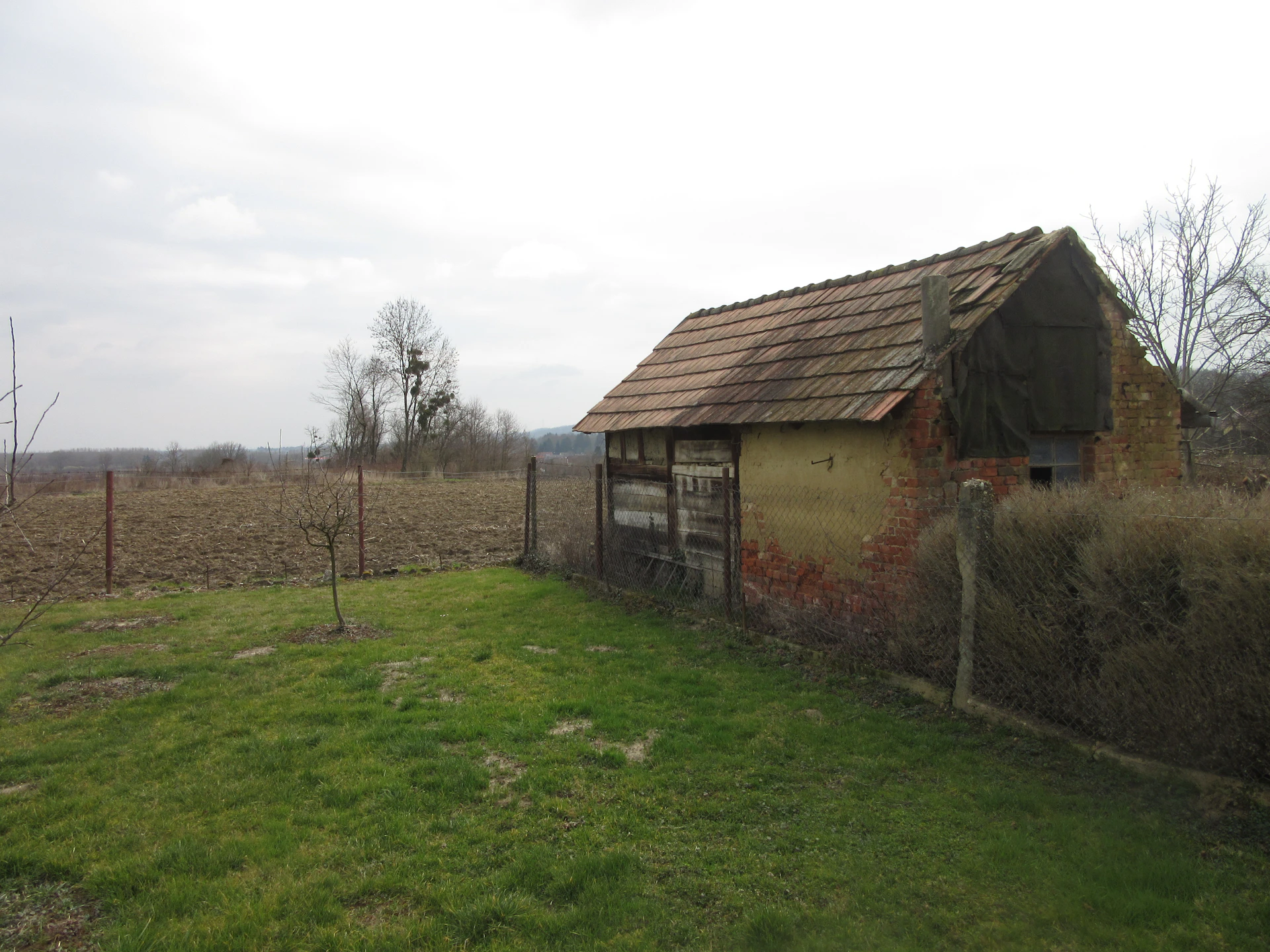 An old barn in a field with a fence