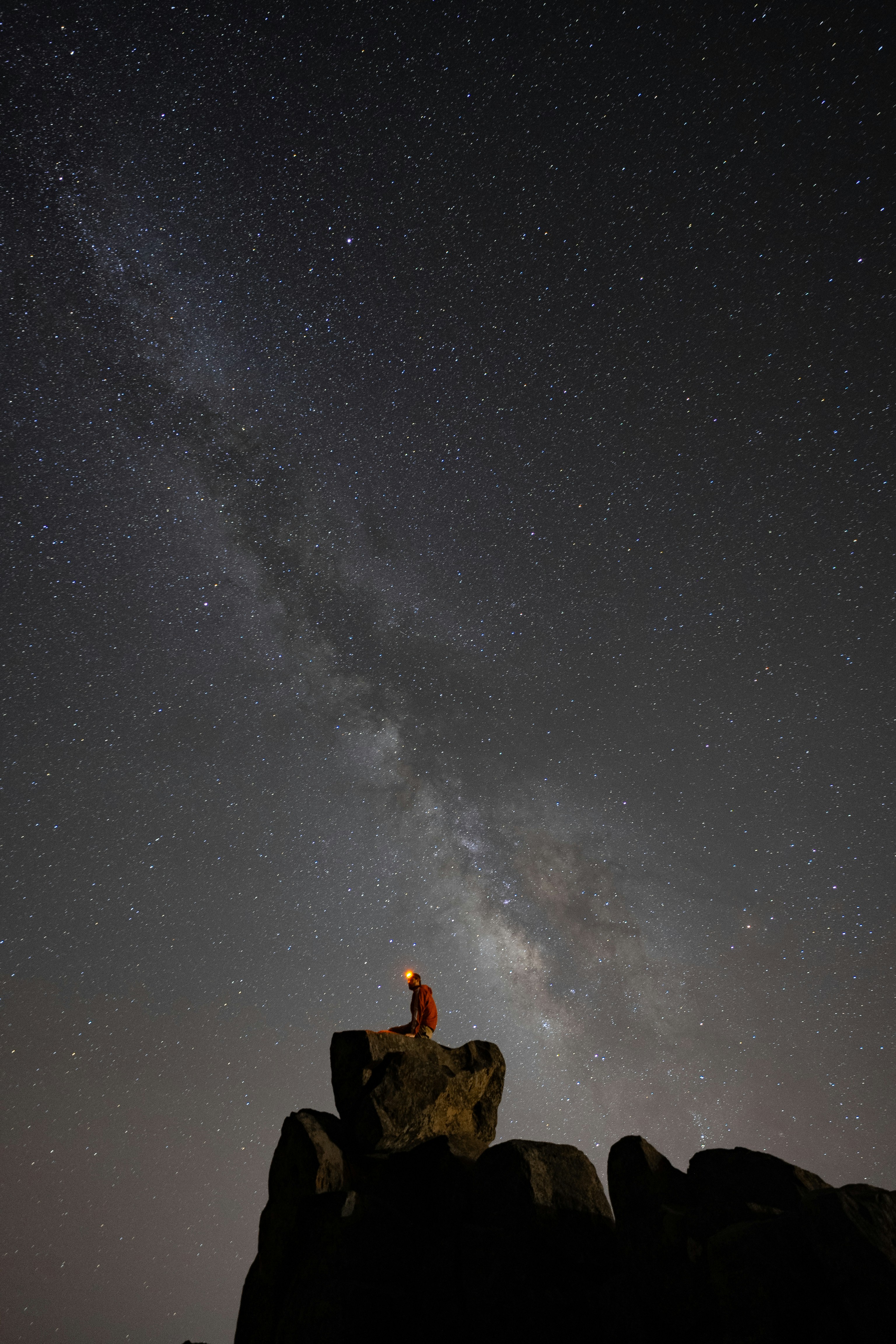 A person standing on top of a rock under a night sky