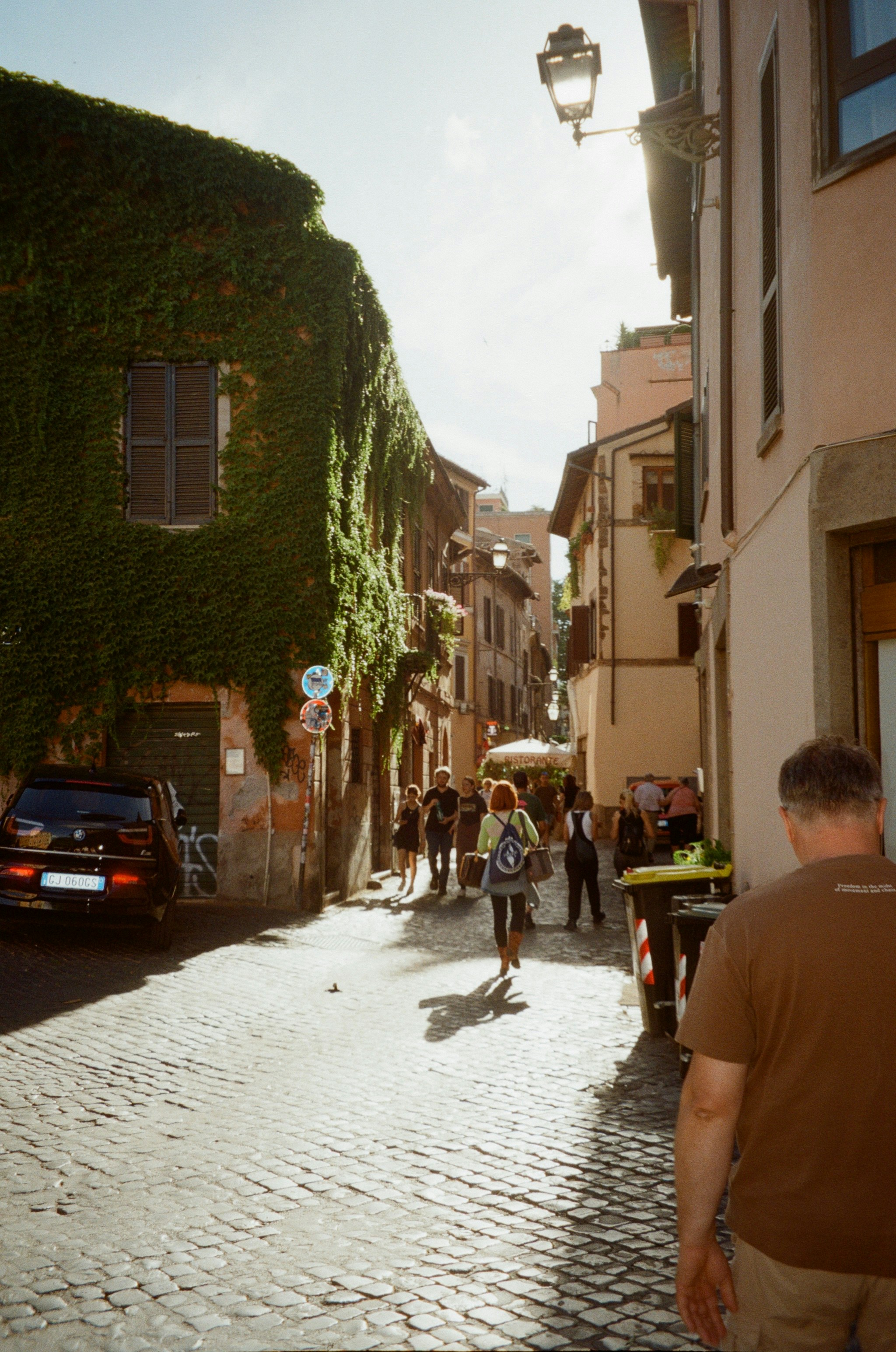 A group of people walking down a cobblestone street photo – Free Rome ...