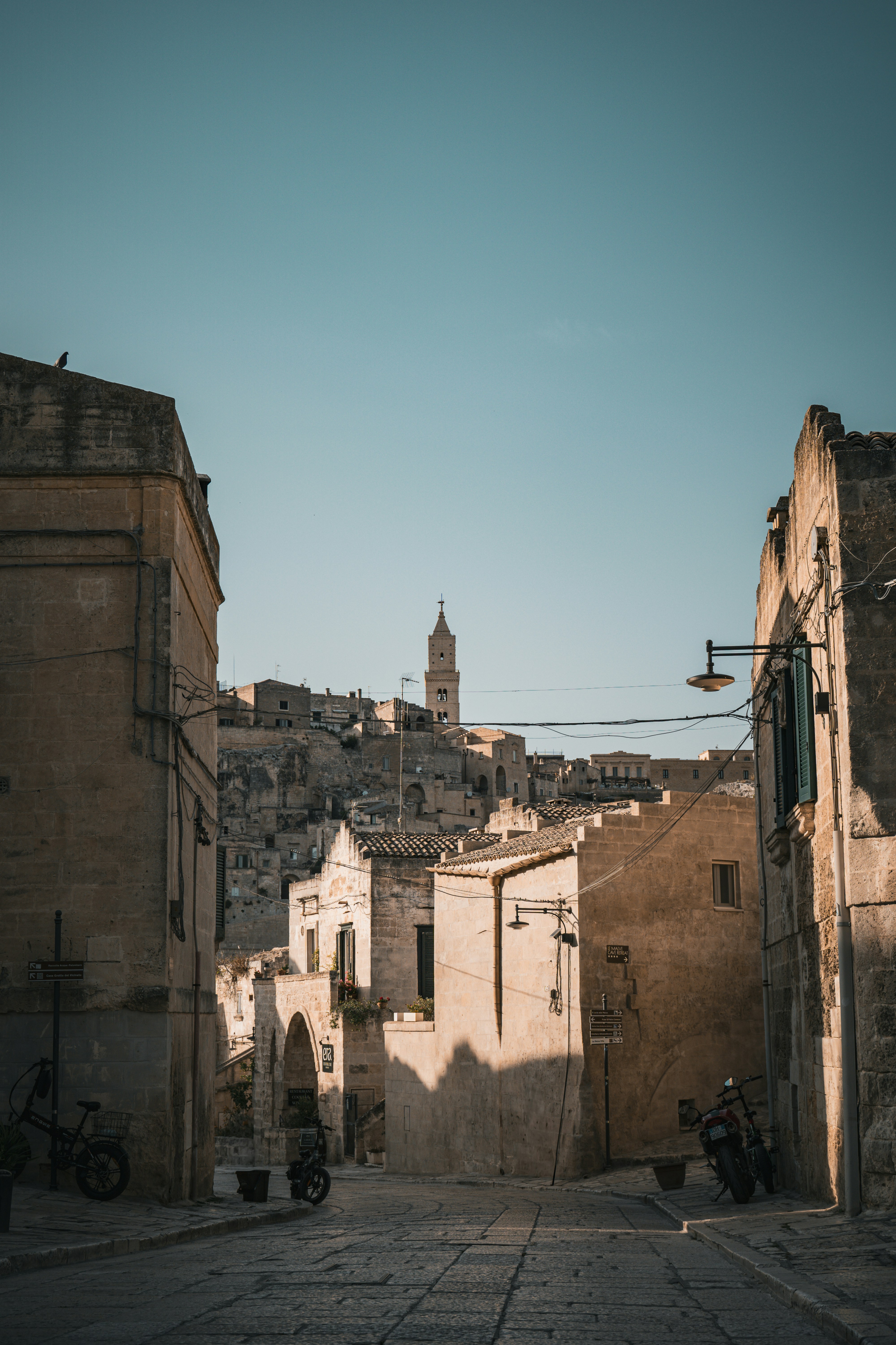 A narrow street with buildings and a clock tower in the background