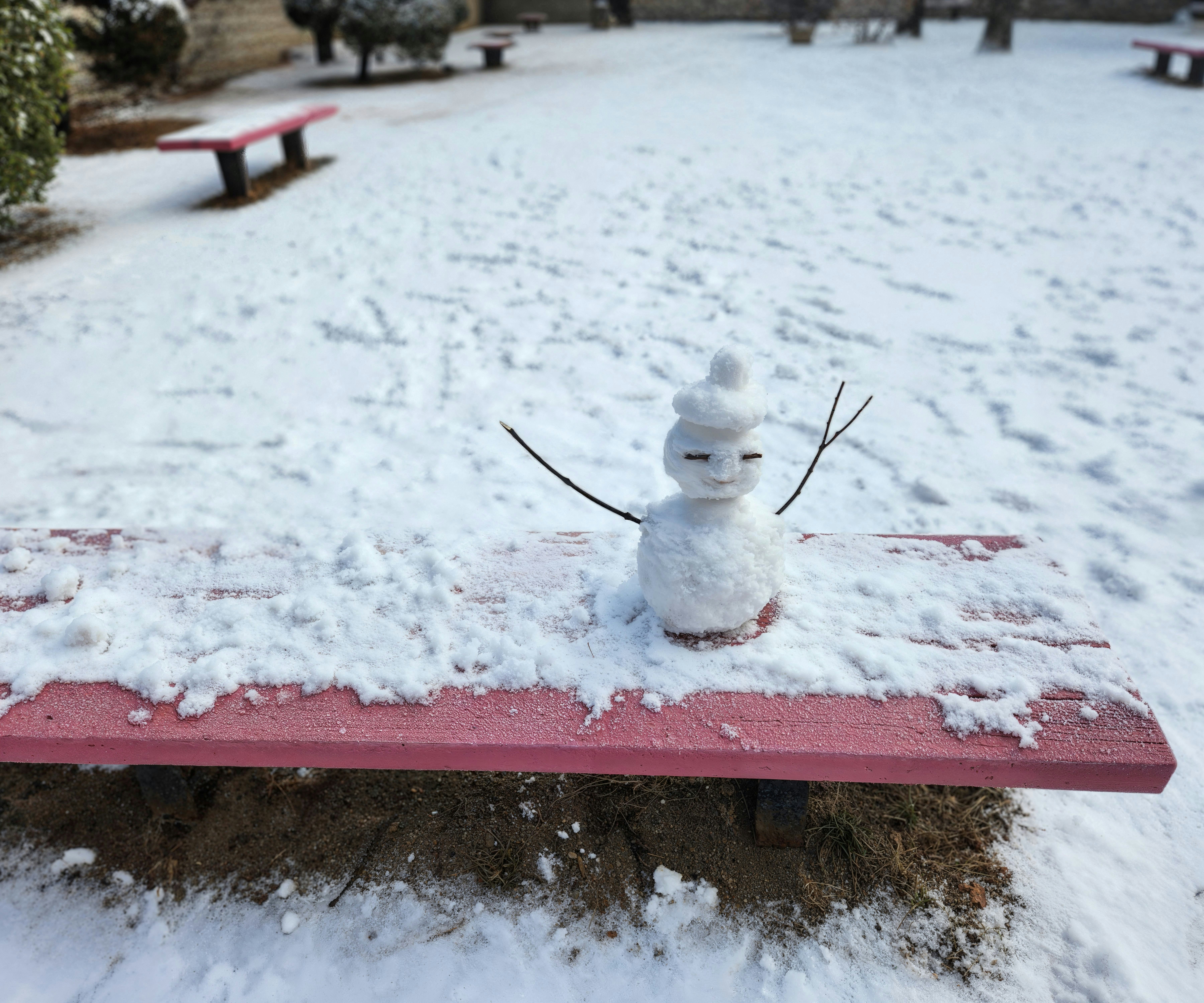 A snowman sitting on top of a red bench