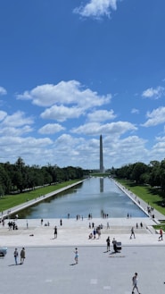 A group of people standing around a fountain in the middle of a park