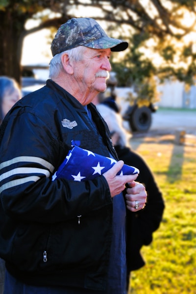 A man in a black jacket holding an american flag
