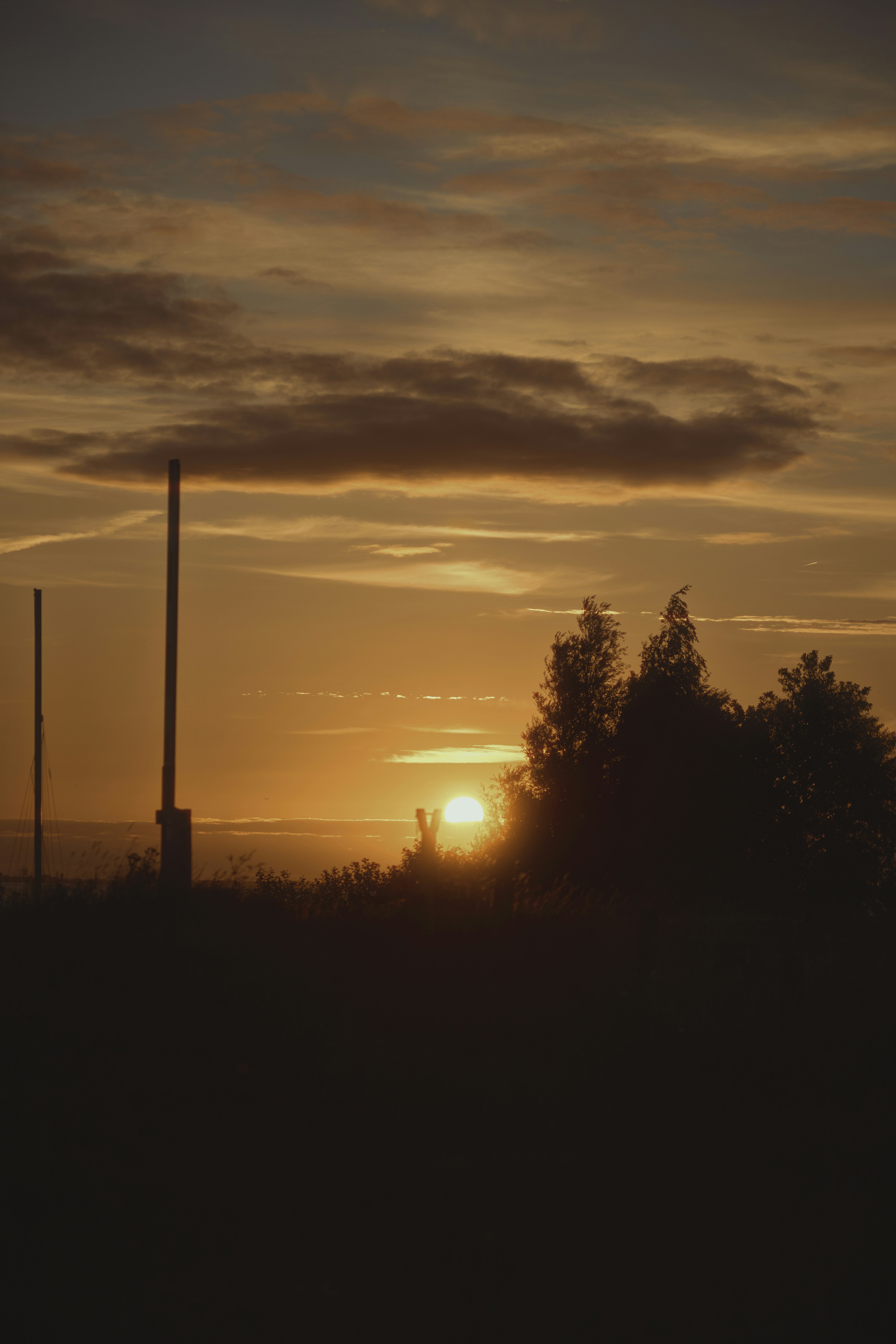 The sun is setting behind a smoke stack
