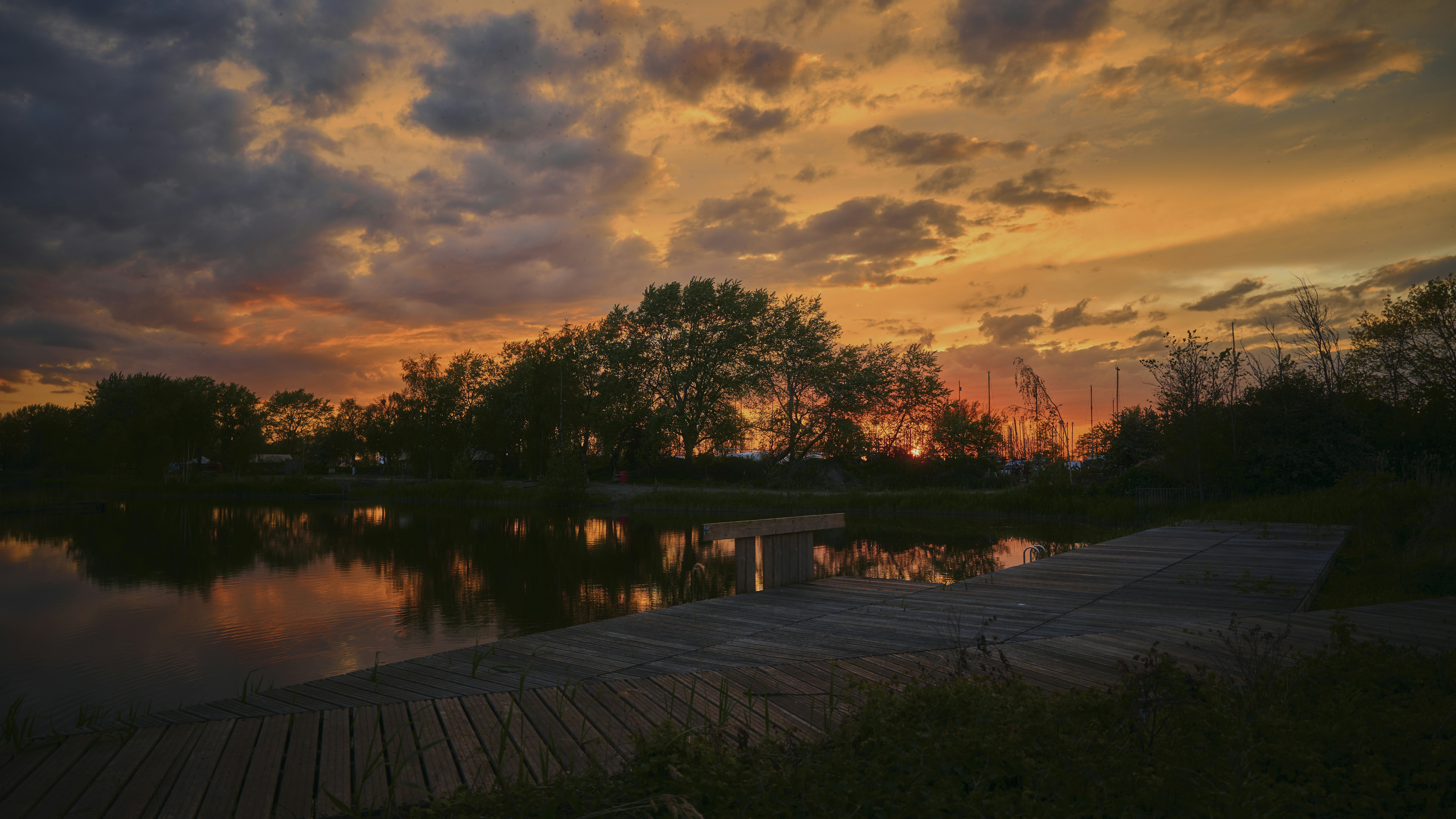 A sunset over a body of water with a dock in the foreground