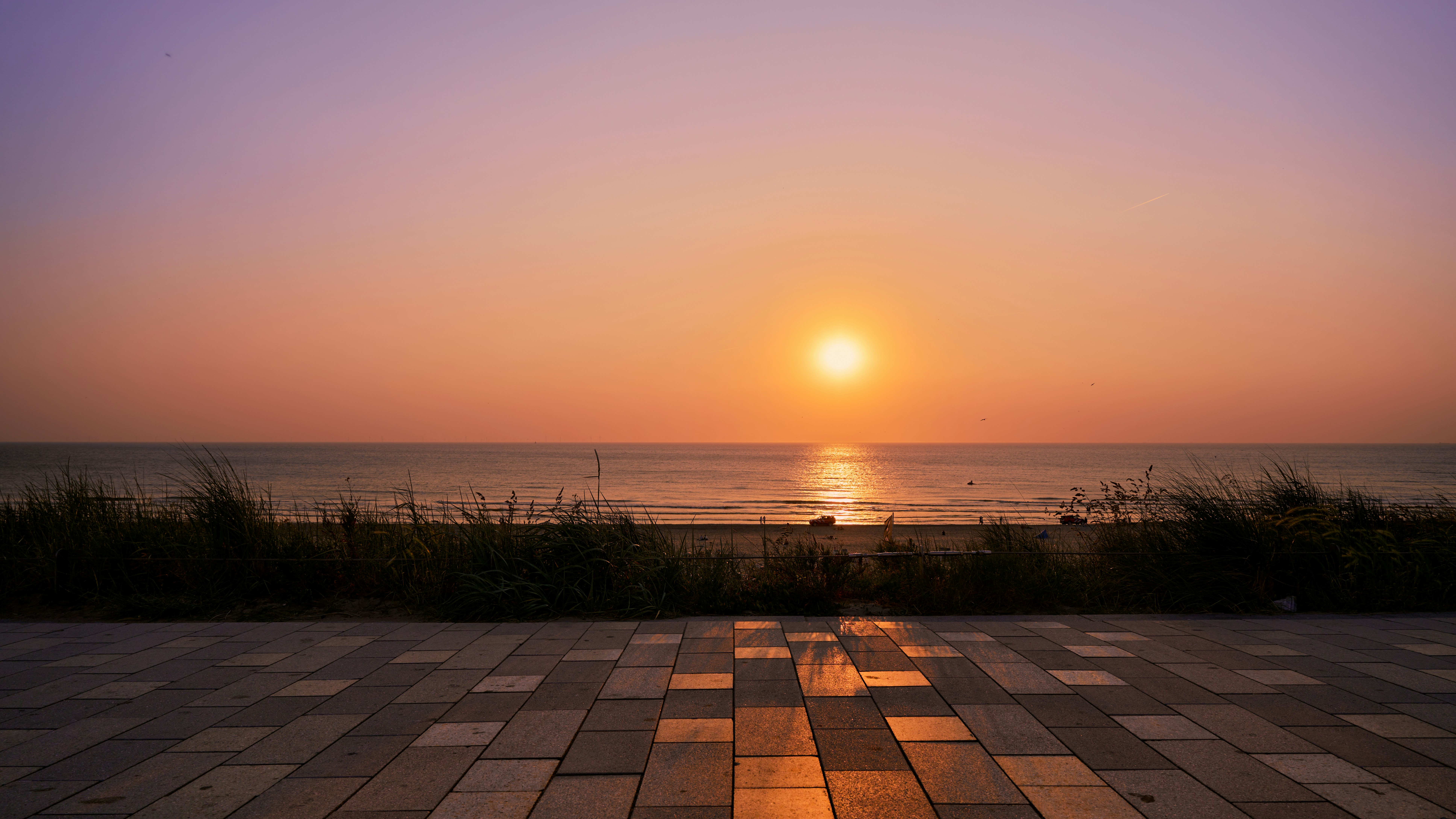 The sun is setting over the ocean on the beach
