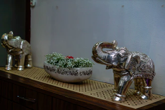 A silver elephant statue next to a bowl of flowers