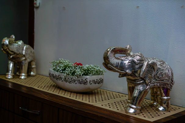A silver elephant statue next to a bowl of flowers