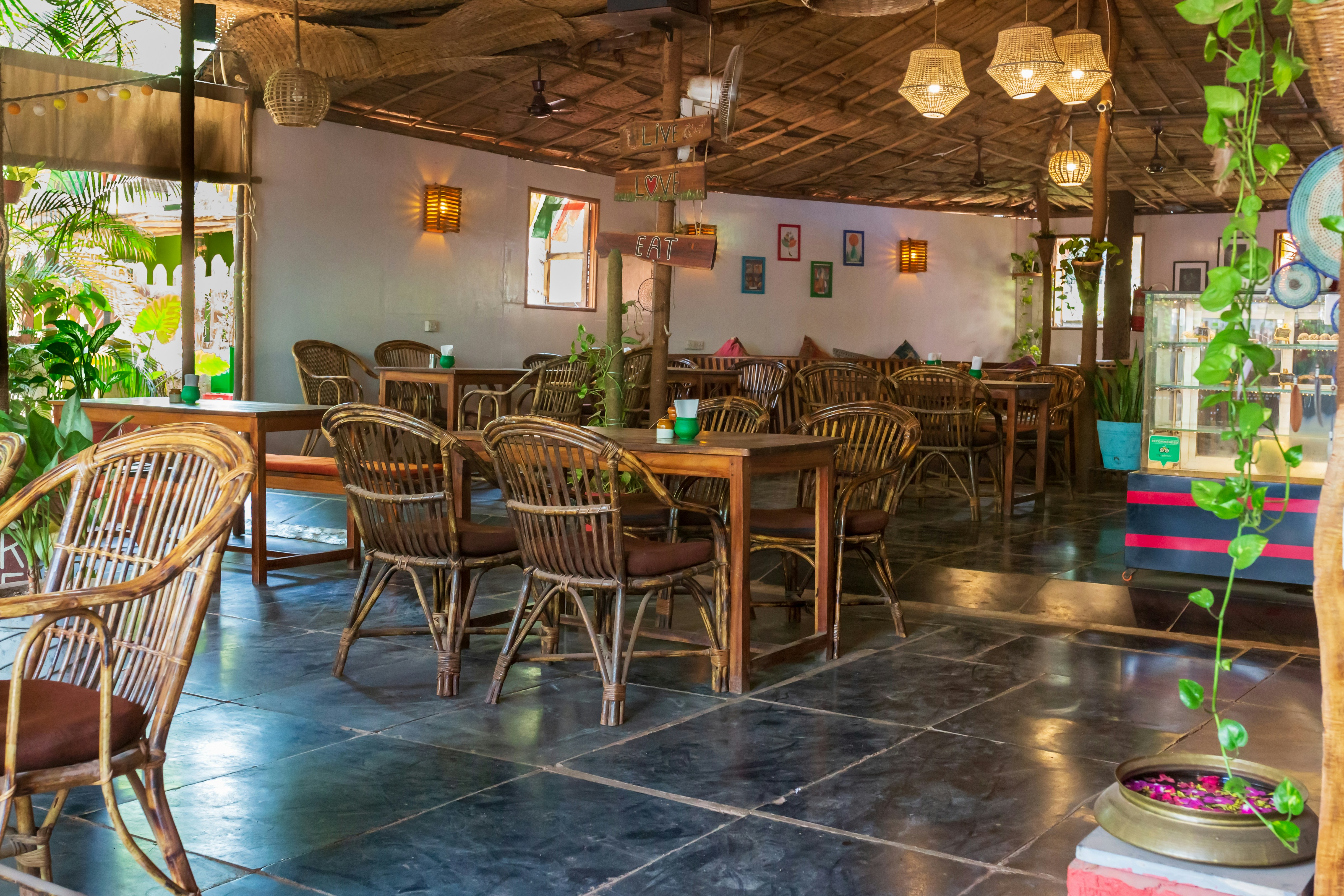 A restaurant with tables, chairs, and potted plants
