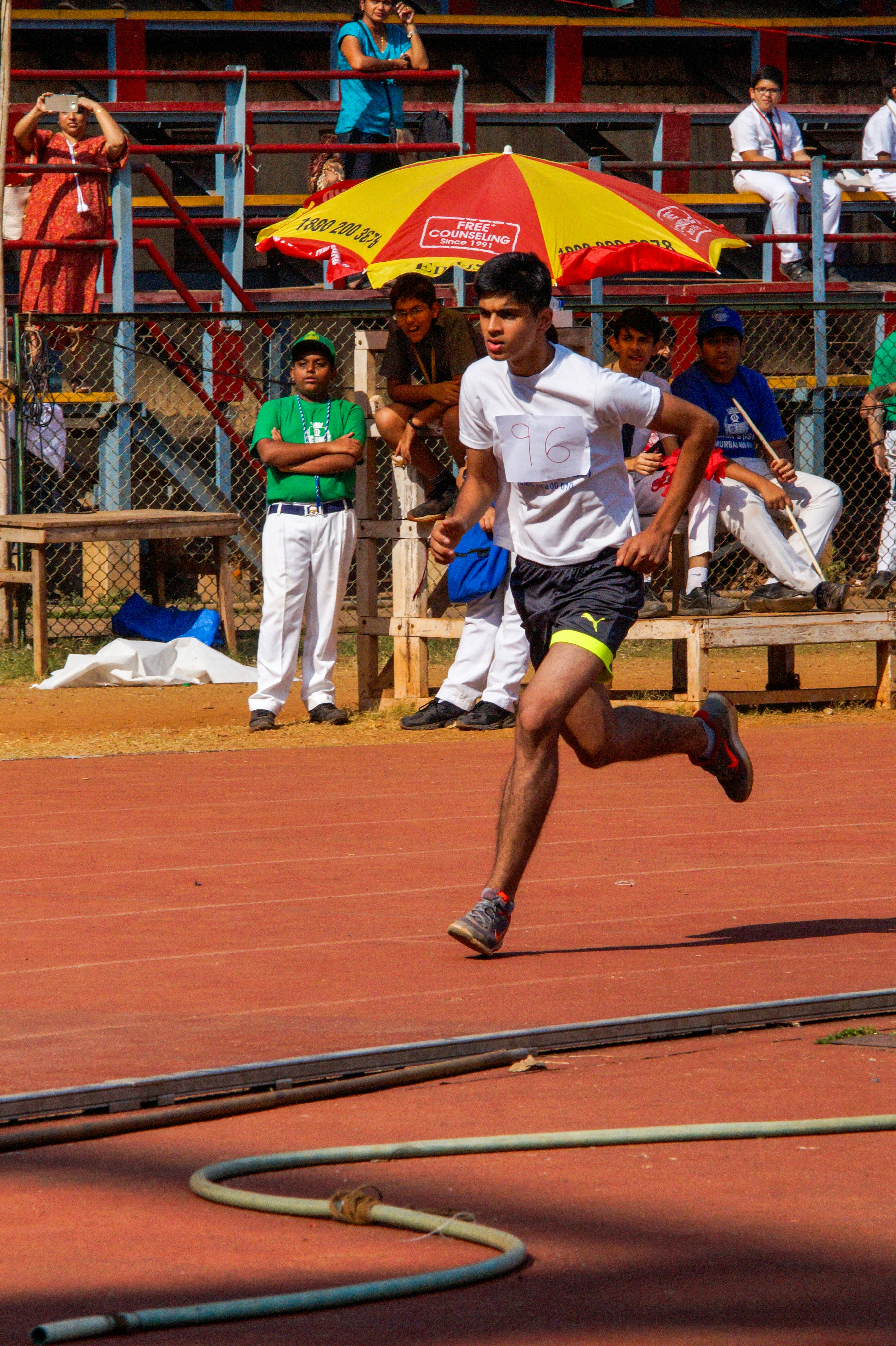 A man running on a track with an umbrella in the background