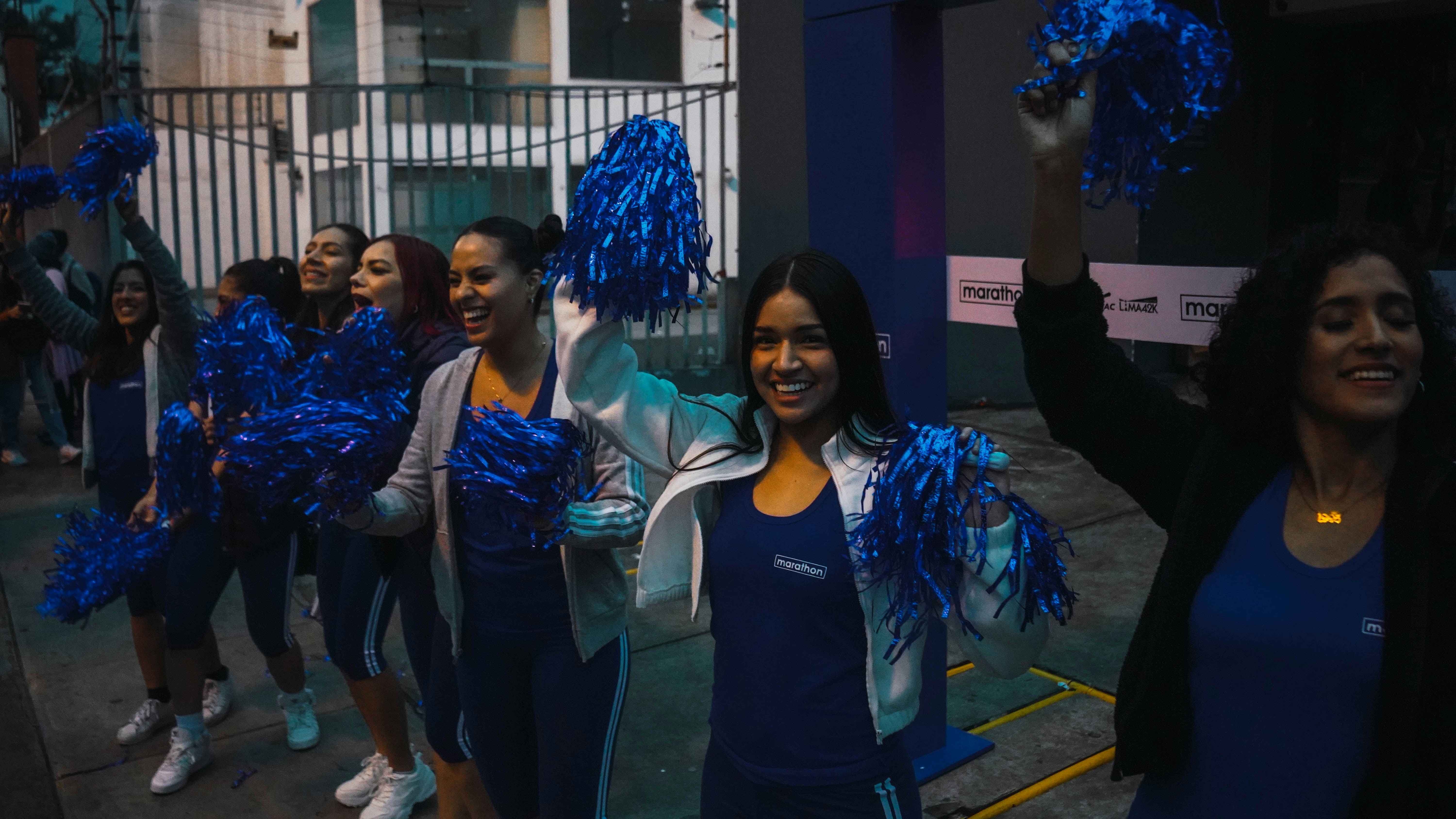 A group of women walking down a street holding blue pom poms