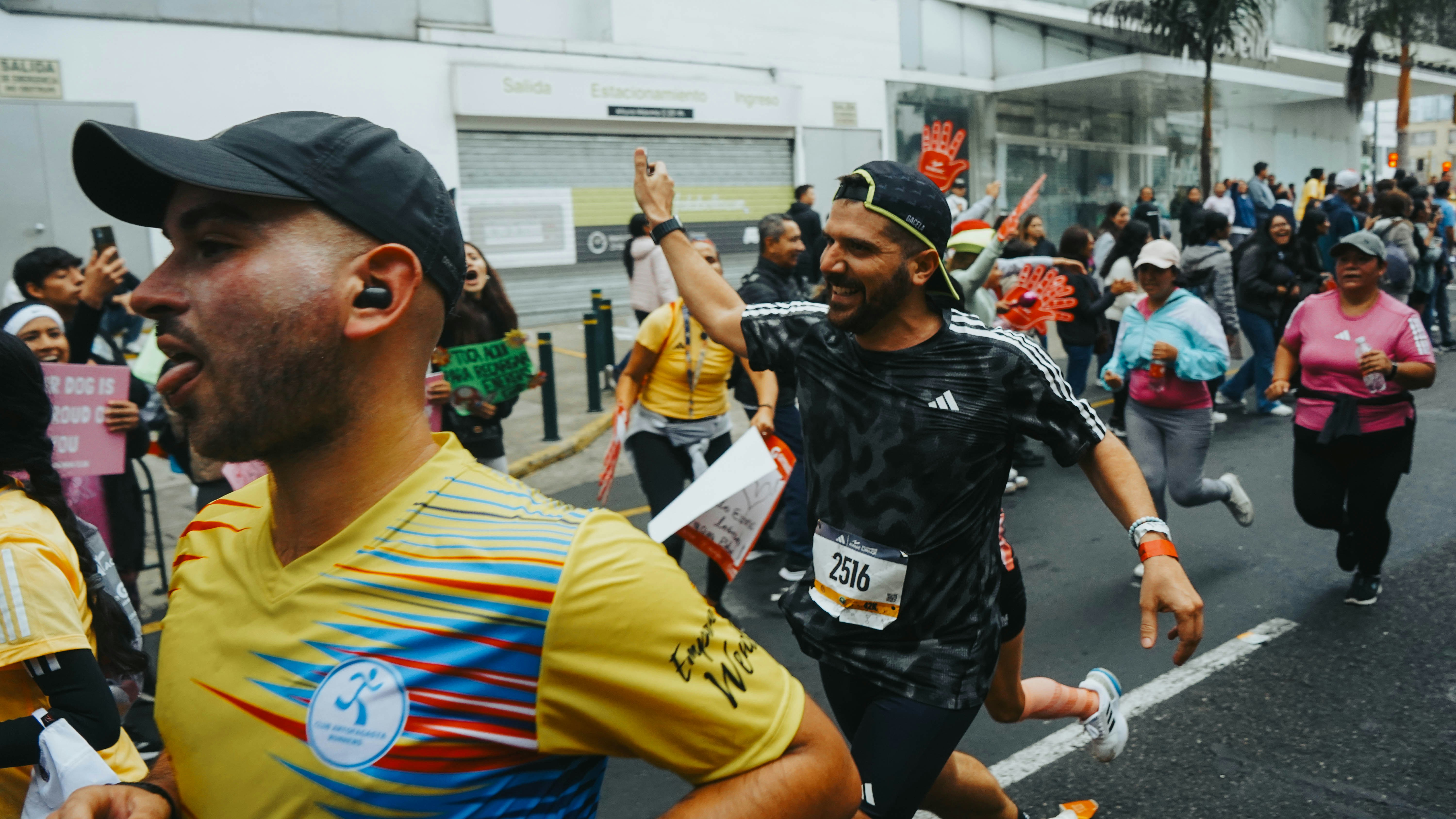 Corredores sonríen y saludan mientras participan en una carrera callejera urbana.