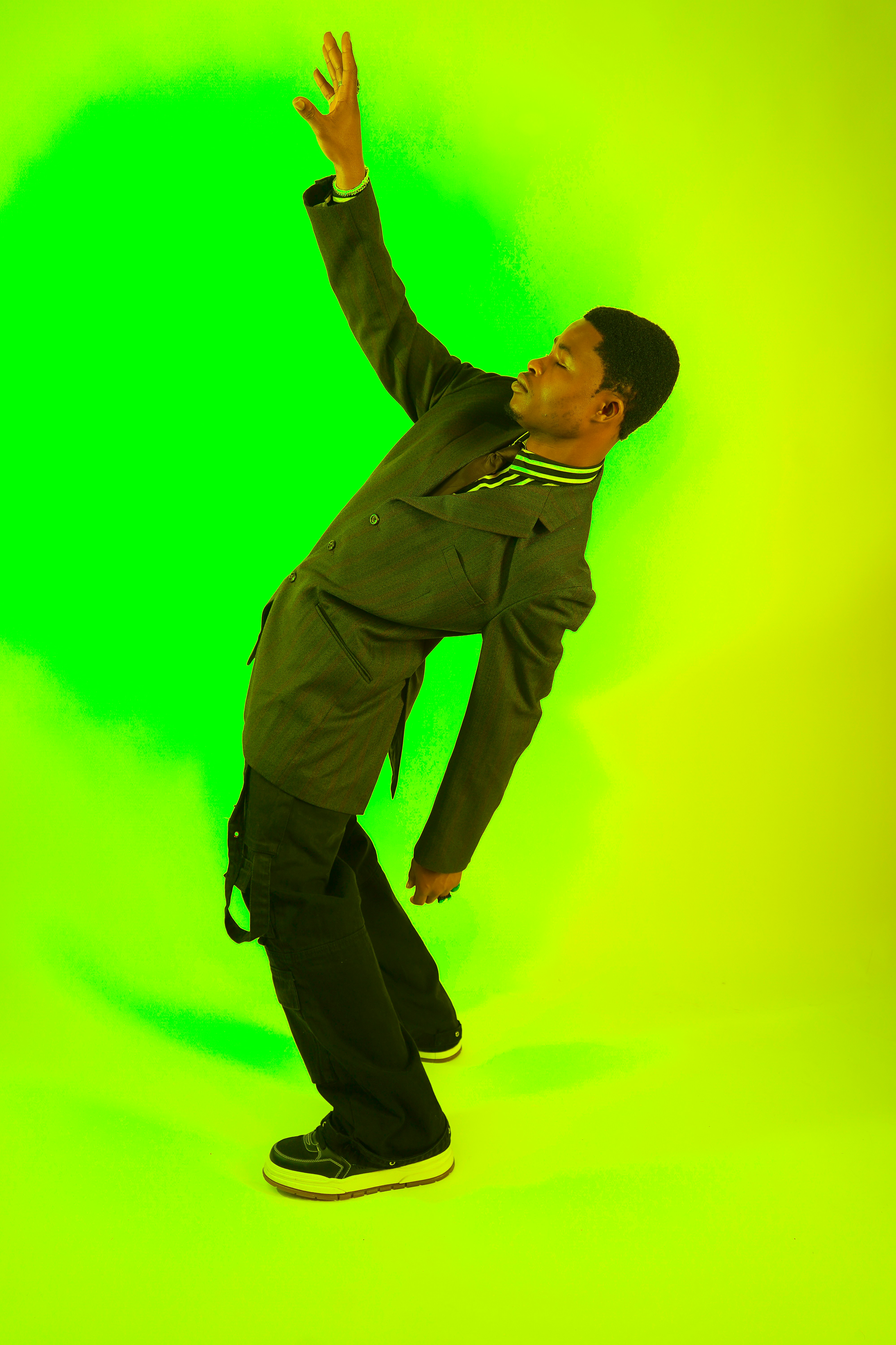 A man in a black suit is dancing on a green background