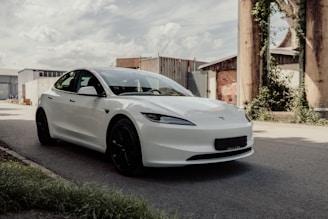 A white car driving down a street next to a building