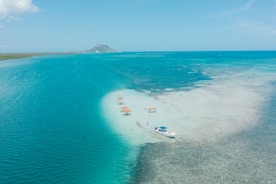 An aerial view of a beach with a boat in the water