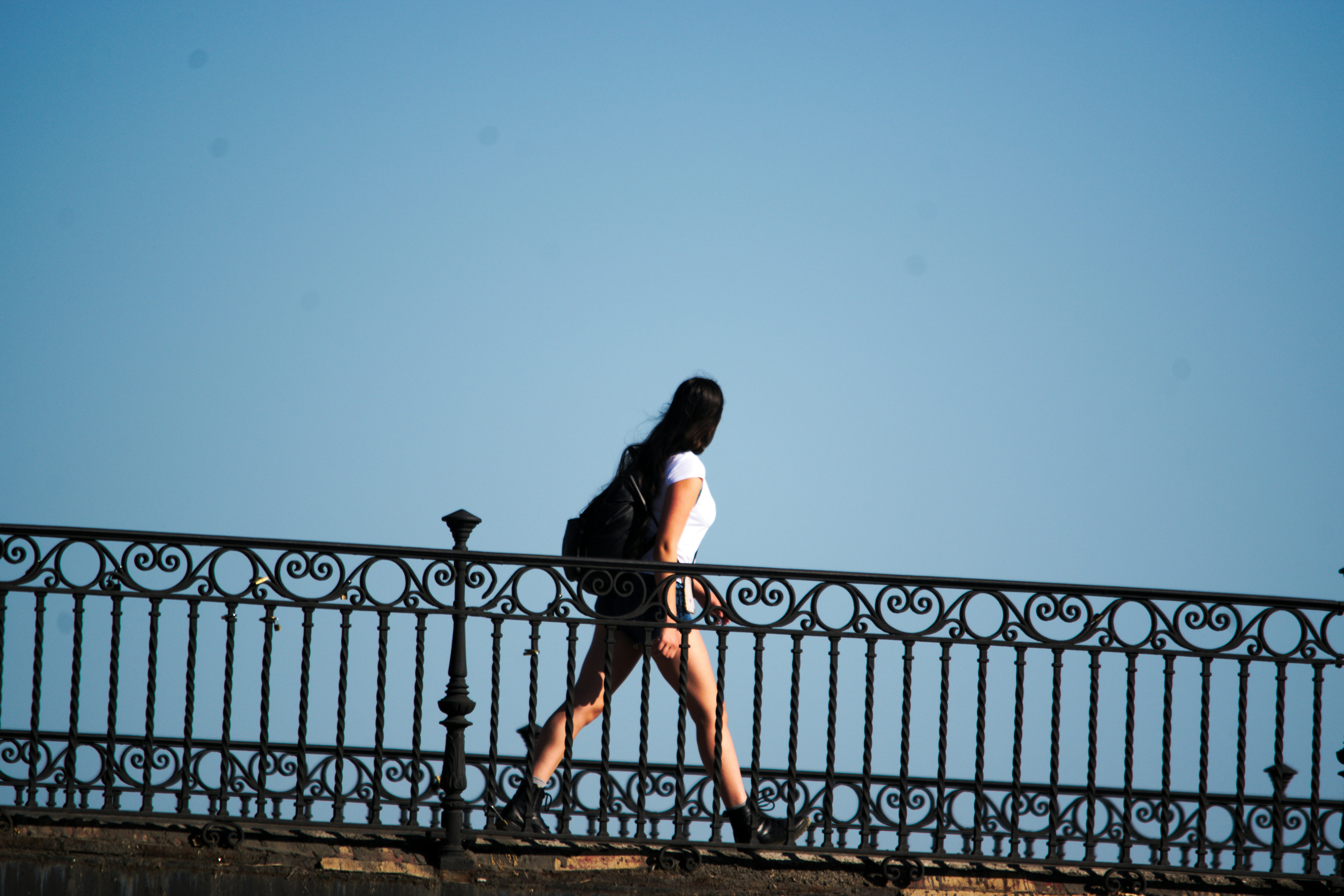 A woman walking across a bridge next to a fence