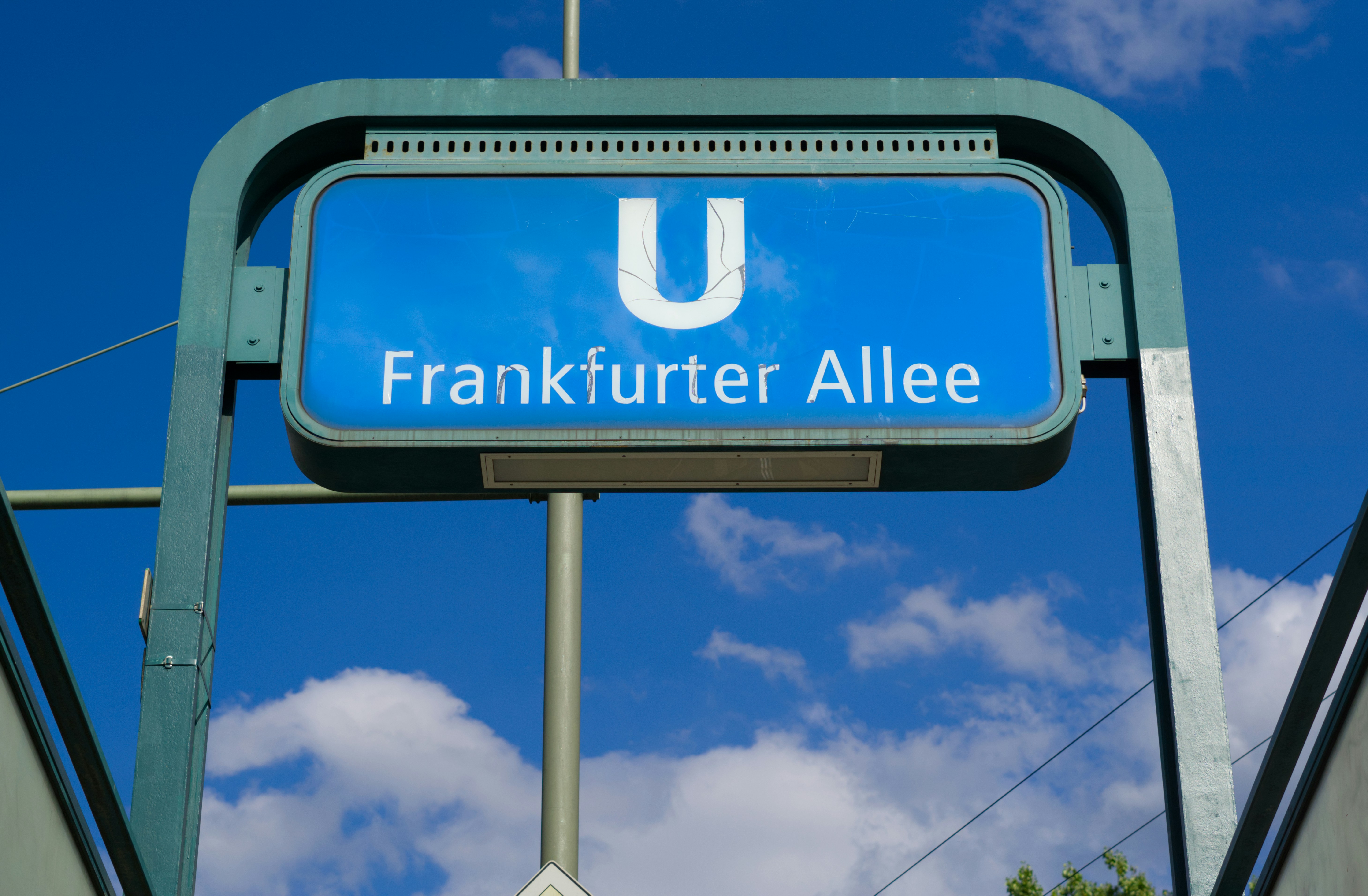 A blue sign that reads frankfurter allee under a blue sky