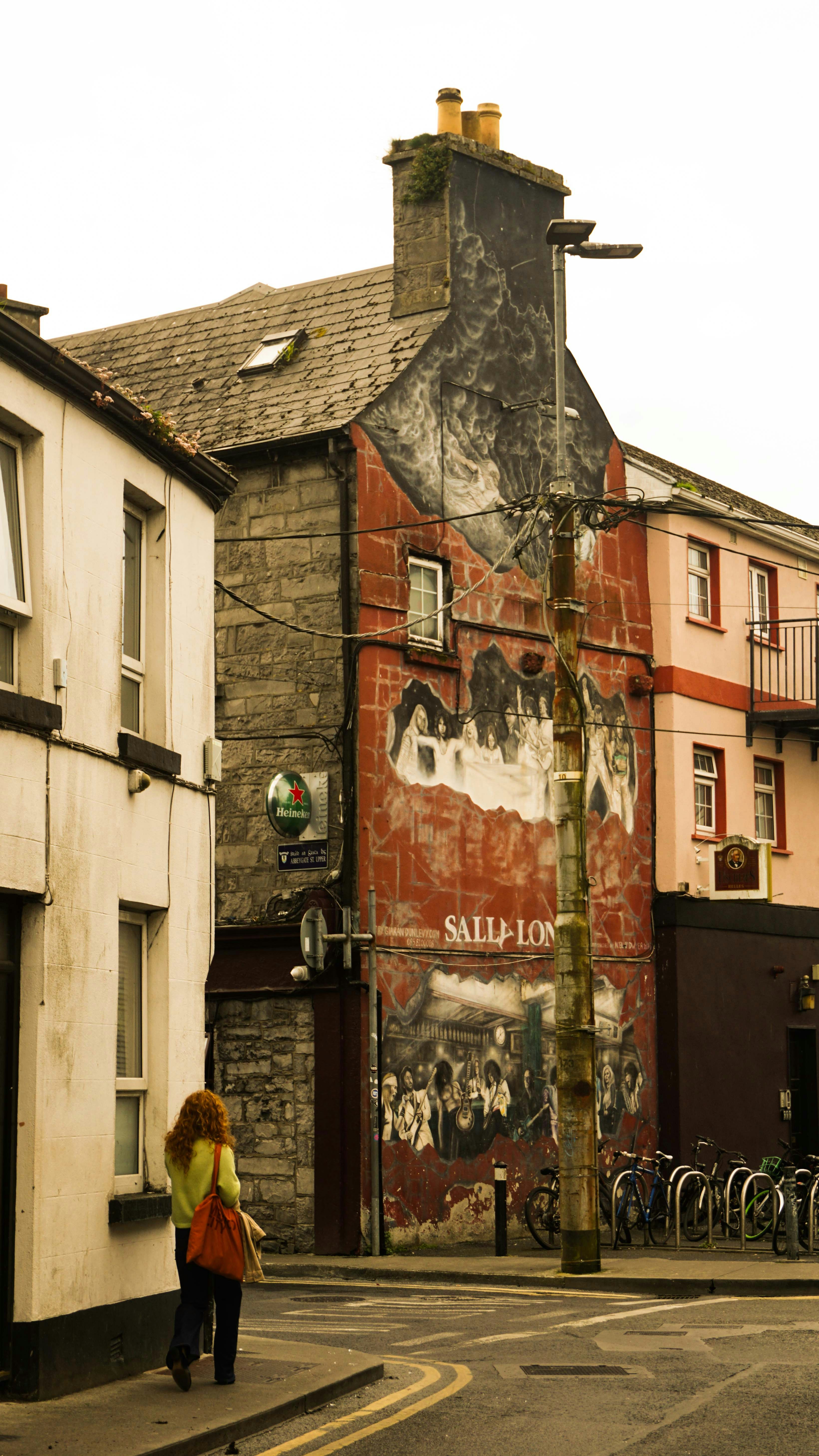 A woman walking down a street next to tall buildings