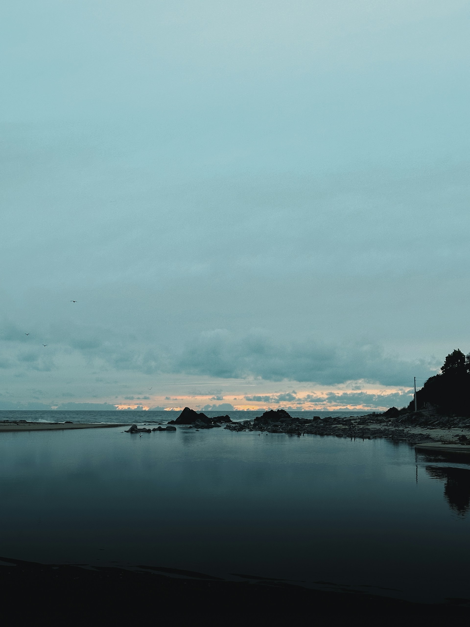 A body of water sitting under a cloudy sky