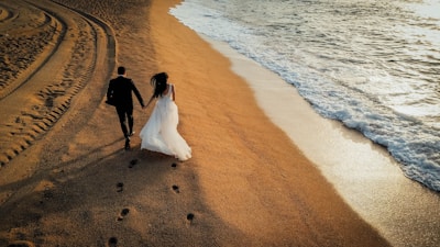 A bride and groom walking on the beach