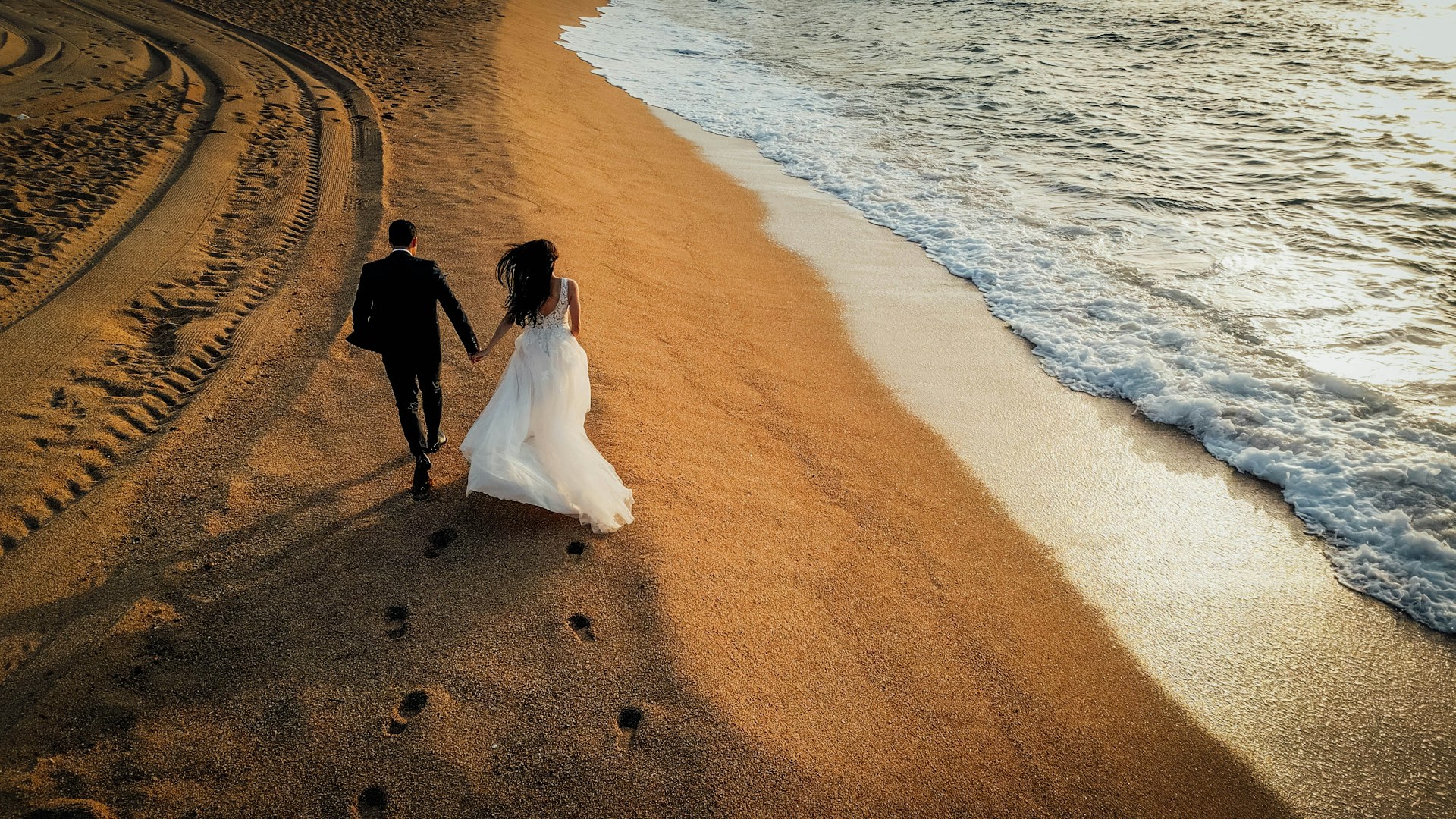 A bride and groom walking on the beach