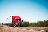 A red semi truck driving down a country road
