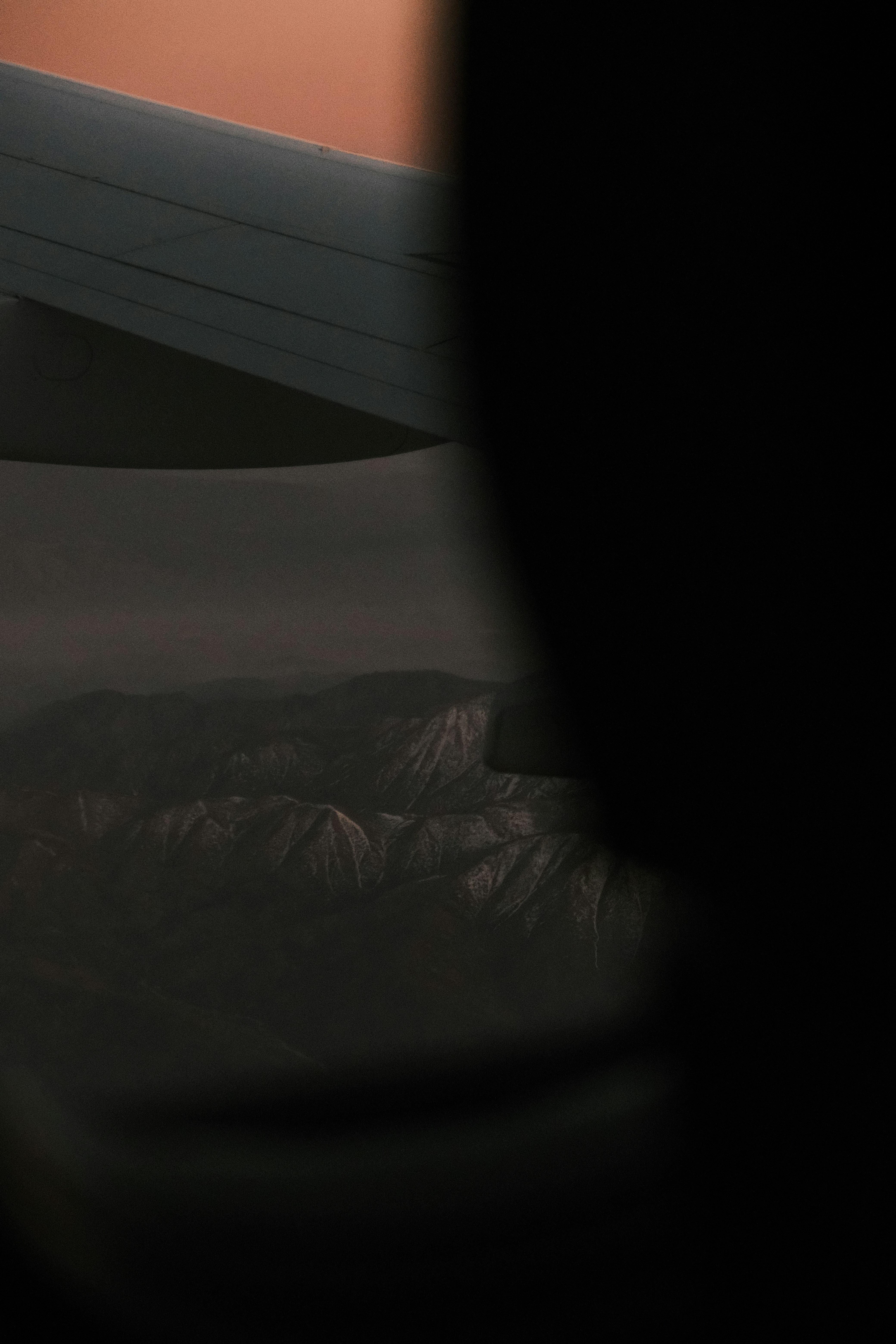 An airplane wing with mountains in the background