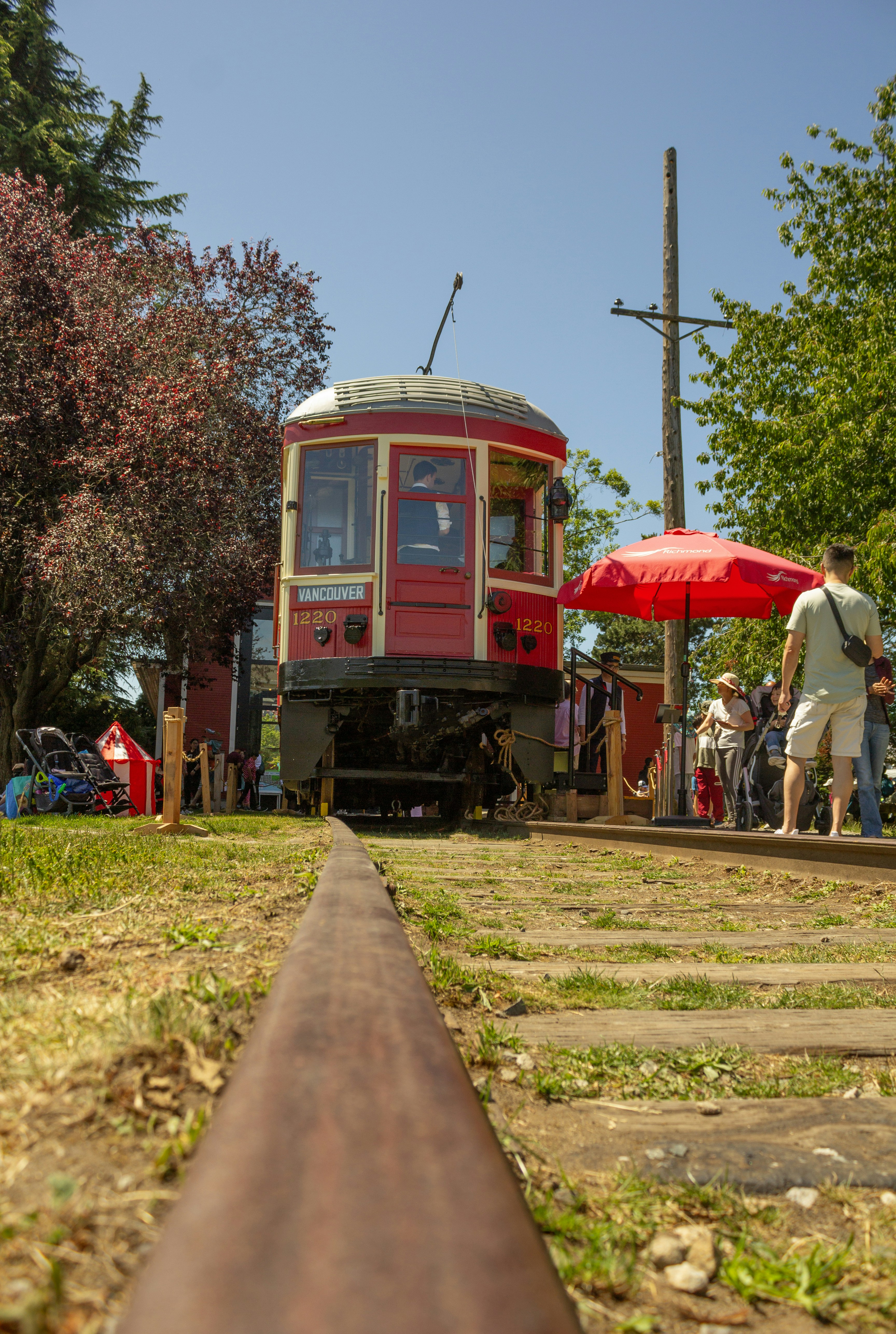 A red train traveling down train tracks next to a forest