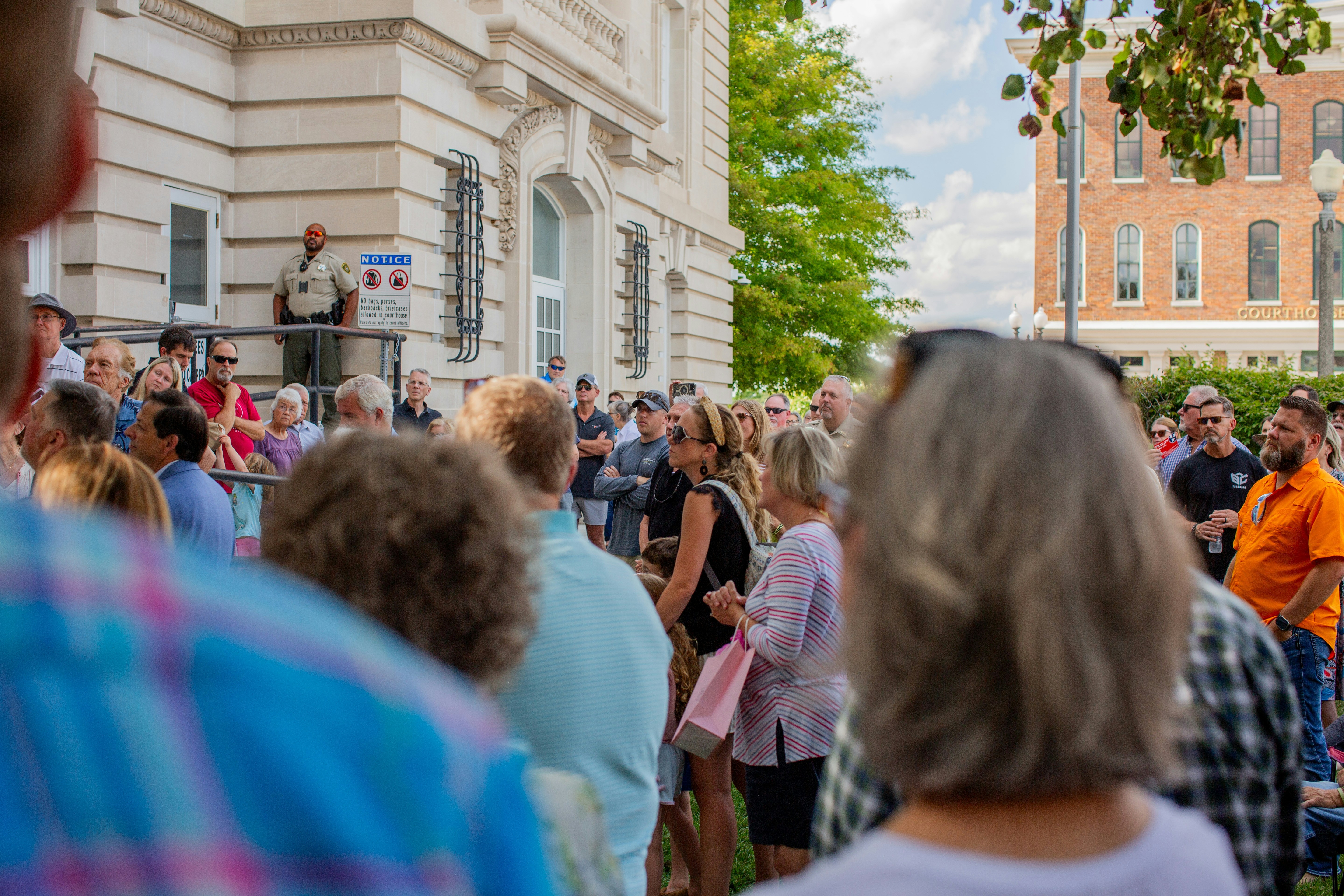 real estate auction bidding crowd - A crowd of people standing in front of a building
