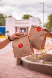 Two people holding brown paper bags with red polka dots