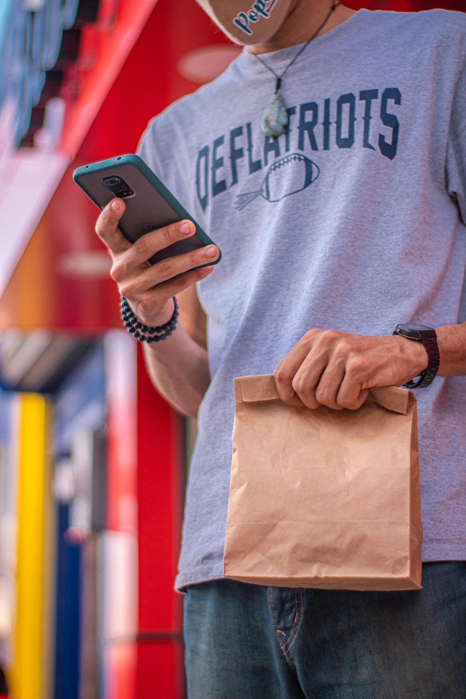 A driver holding a sealed order bag while checking the next stop on a phone, the working view a driver app has to get right