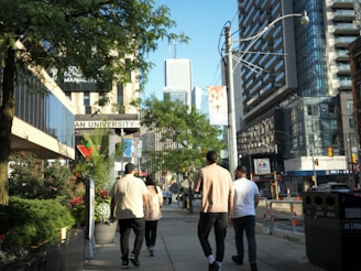 A group of men walking down a street next to tall buildings
