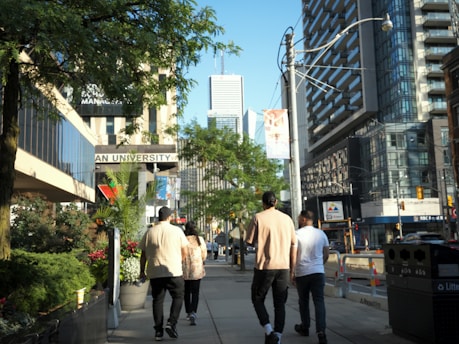 A group of men walking down a street next to tall buildings