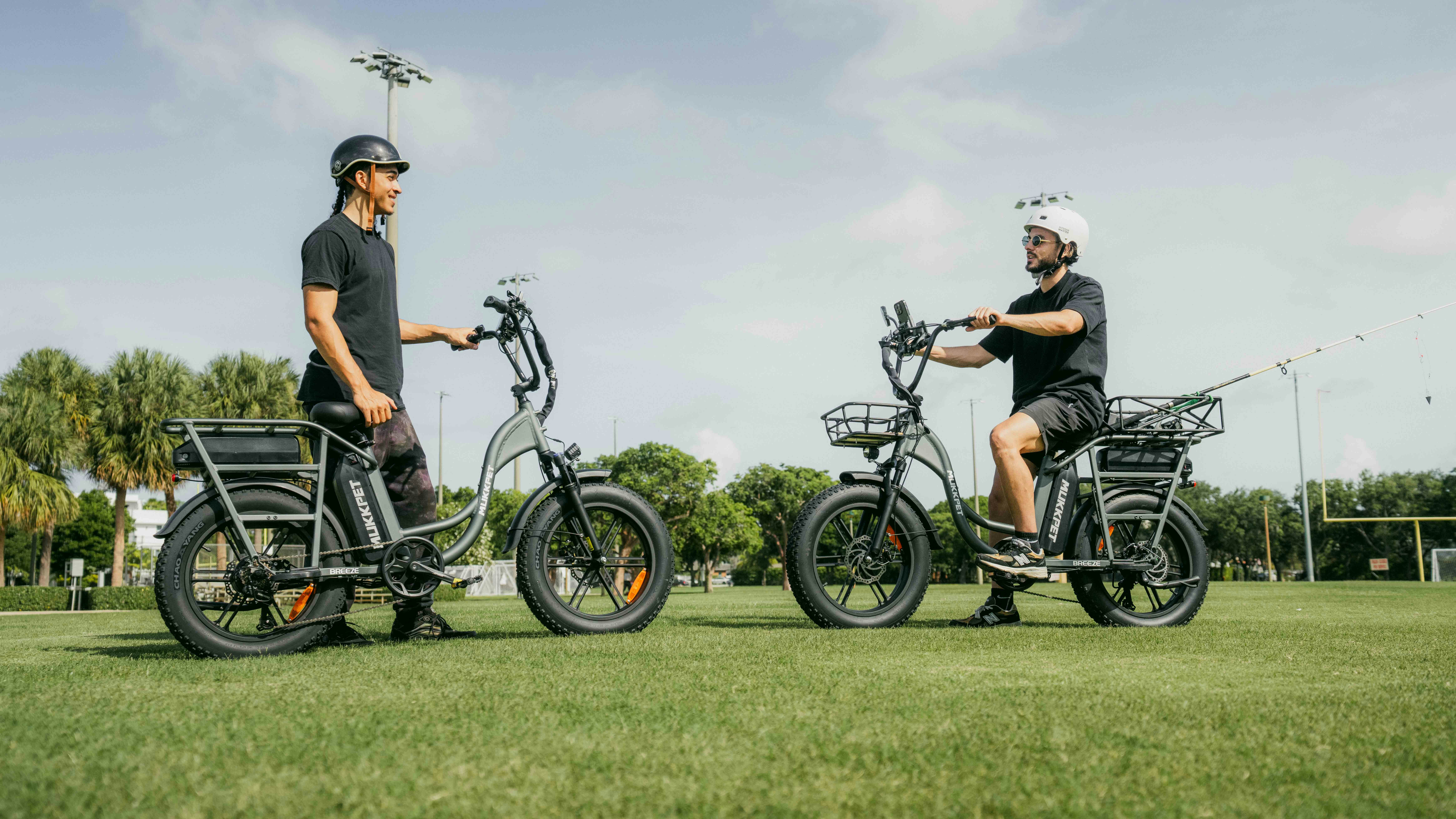 A couple of men standing next to each other on bikes