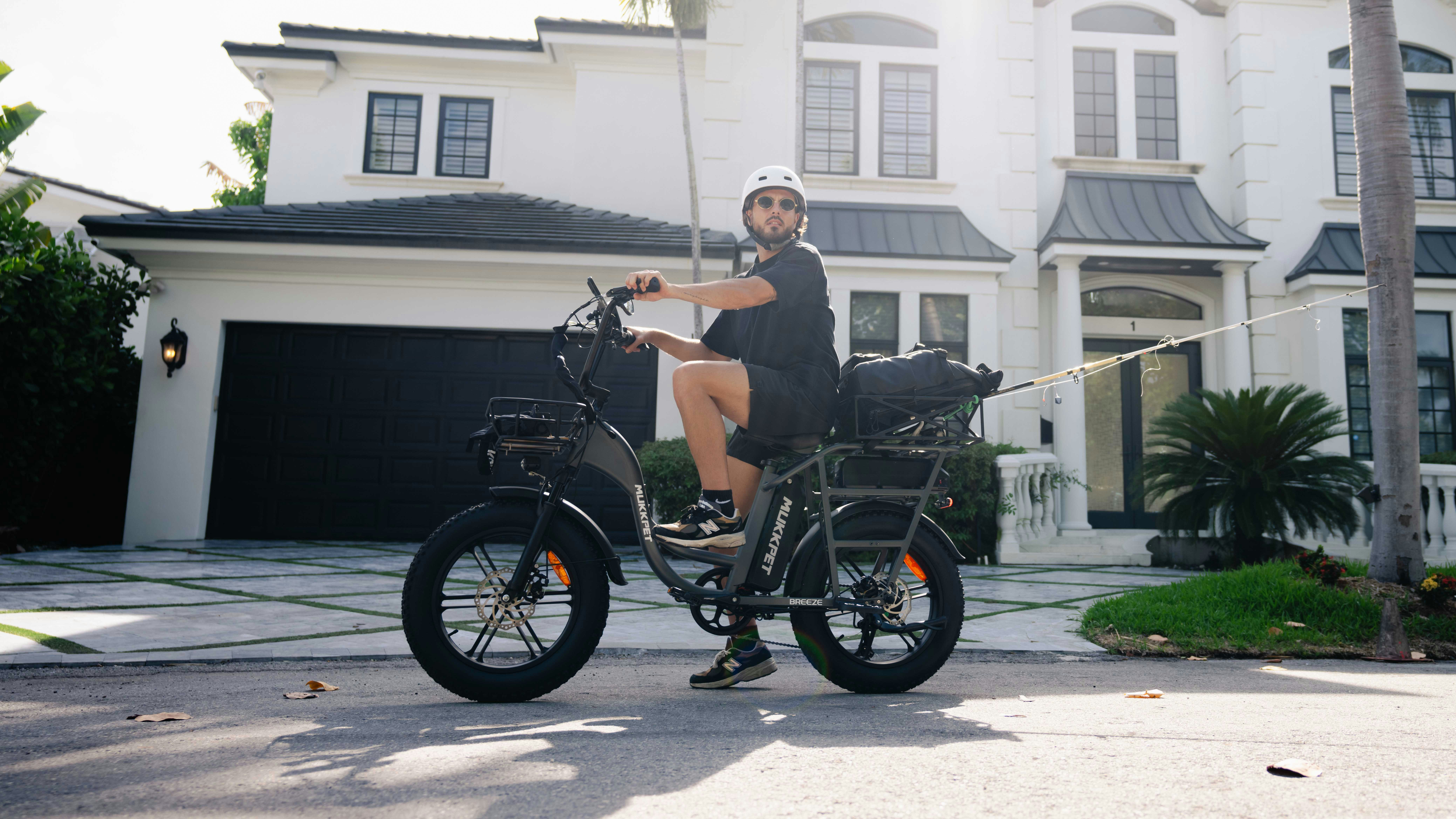 A man riding a motorcycle in front of a large house