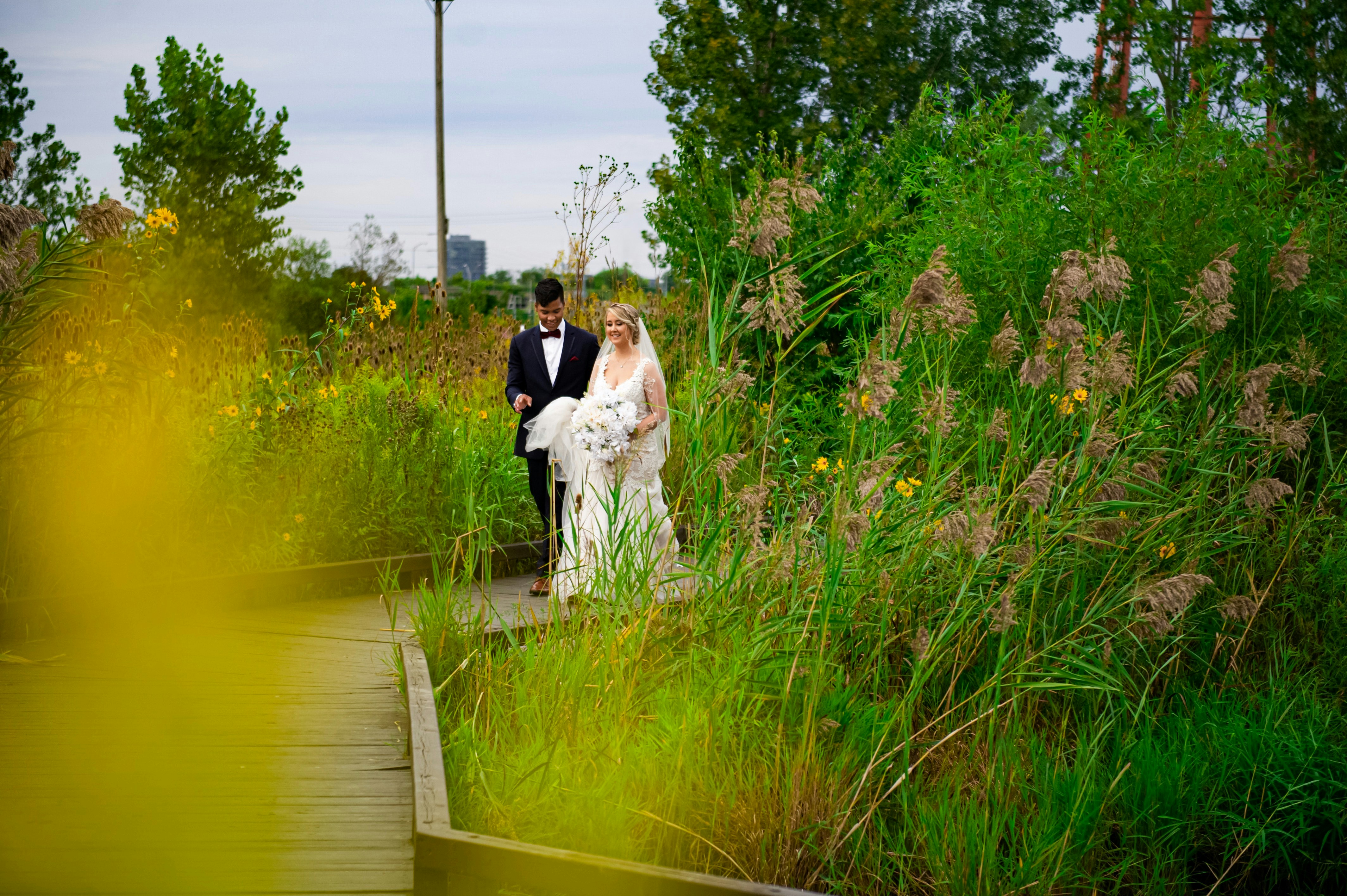 Una novia y un novio caminando por la hierba alta
