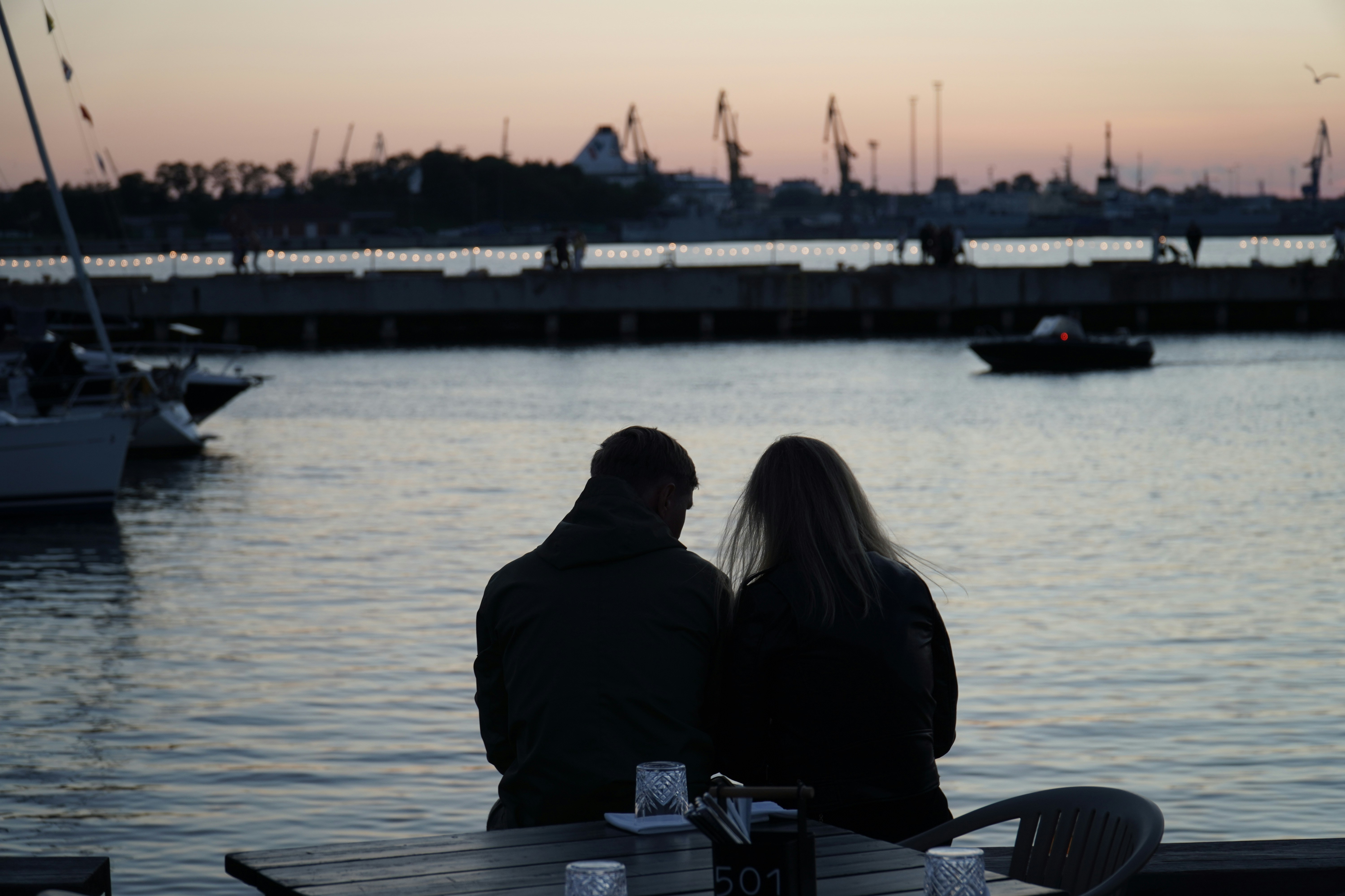 Two people sitting at a table looking out over the water