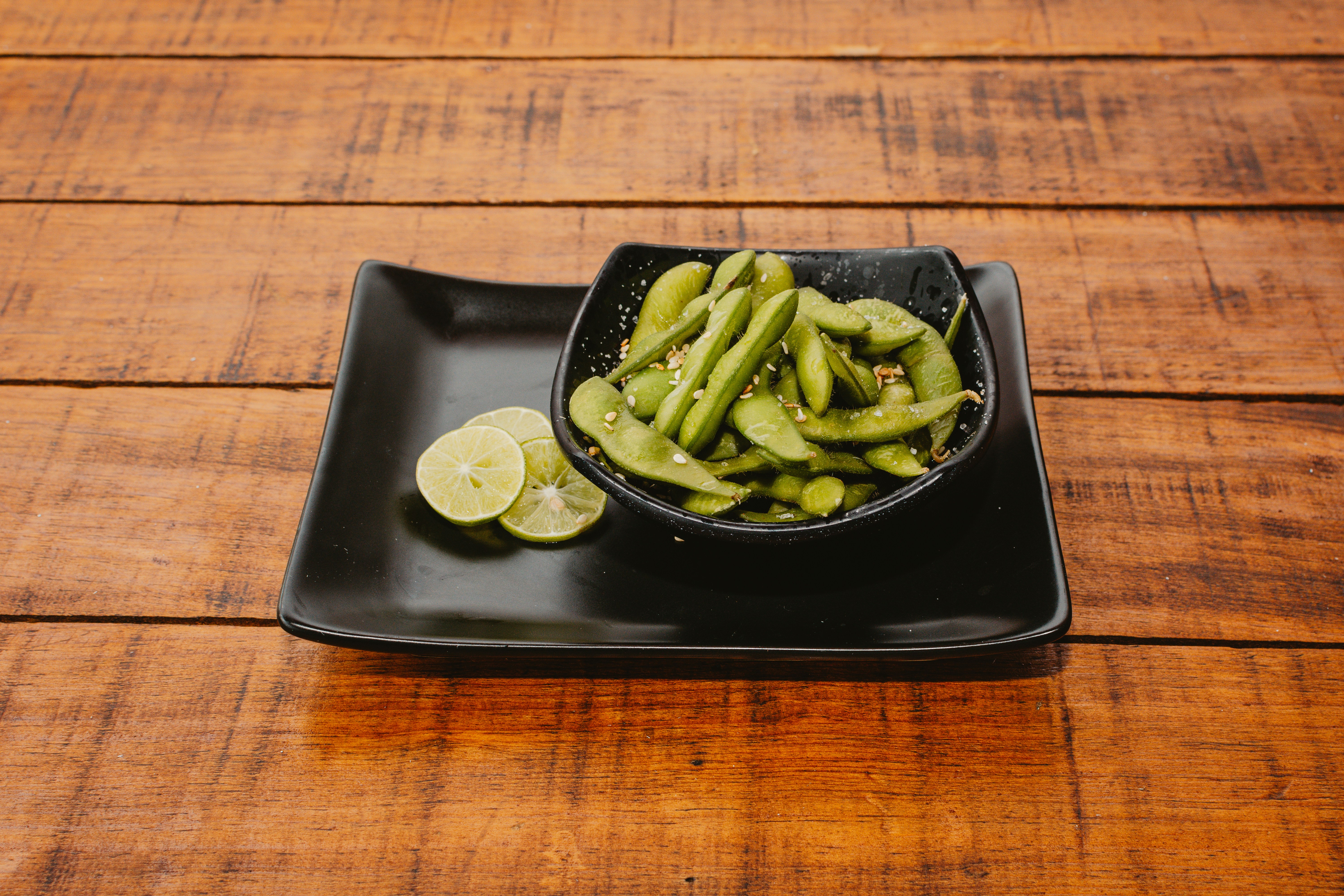 Edamame pods in a black bowl with lime