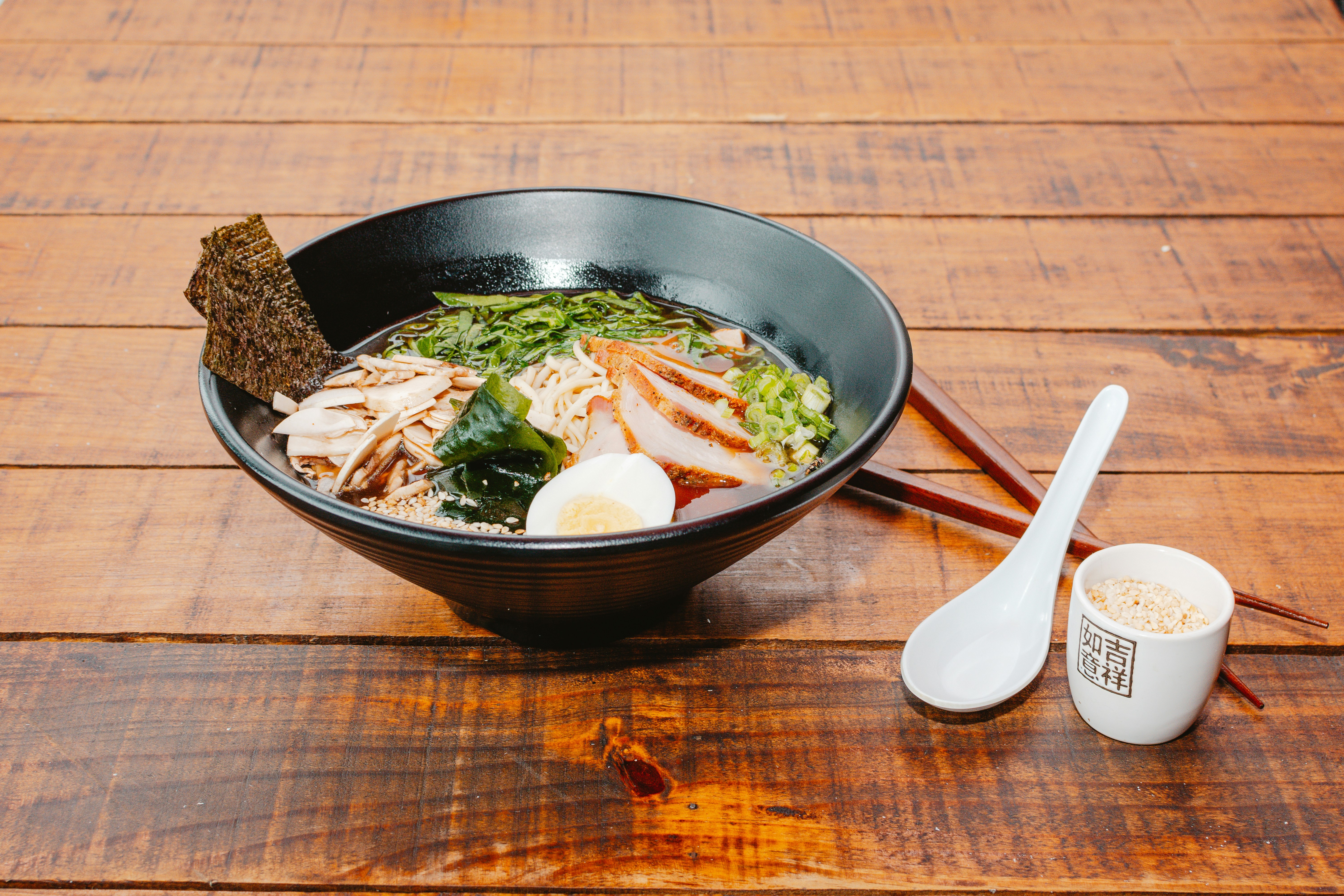 A bowl of food with chopsticks on a wooden table