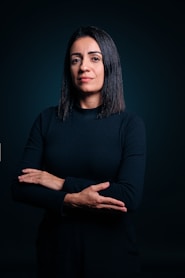 A woman standing with her arms crossed in front of a dark background