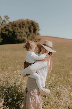 A woman holding a baby in a field